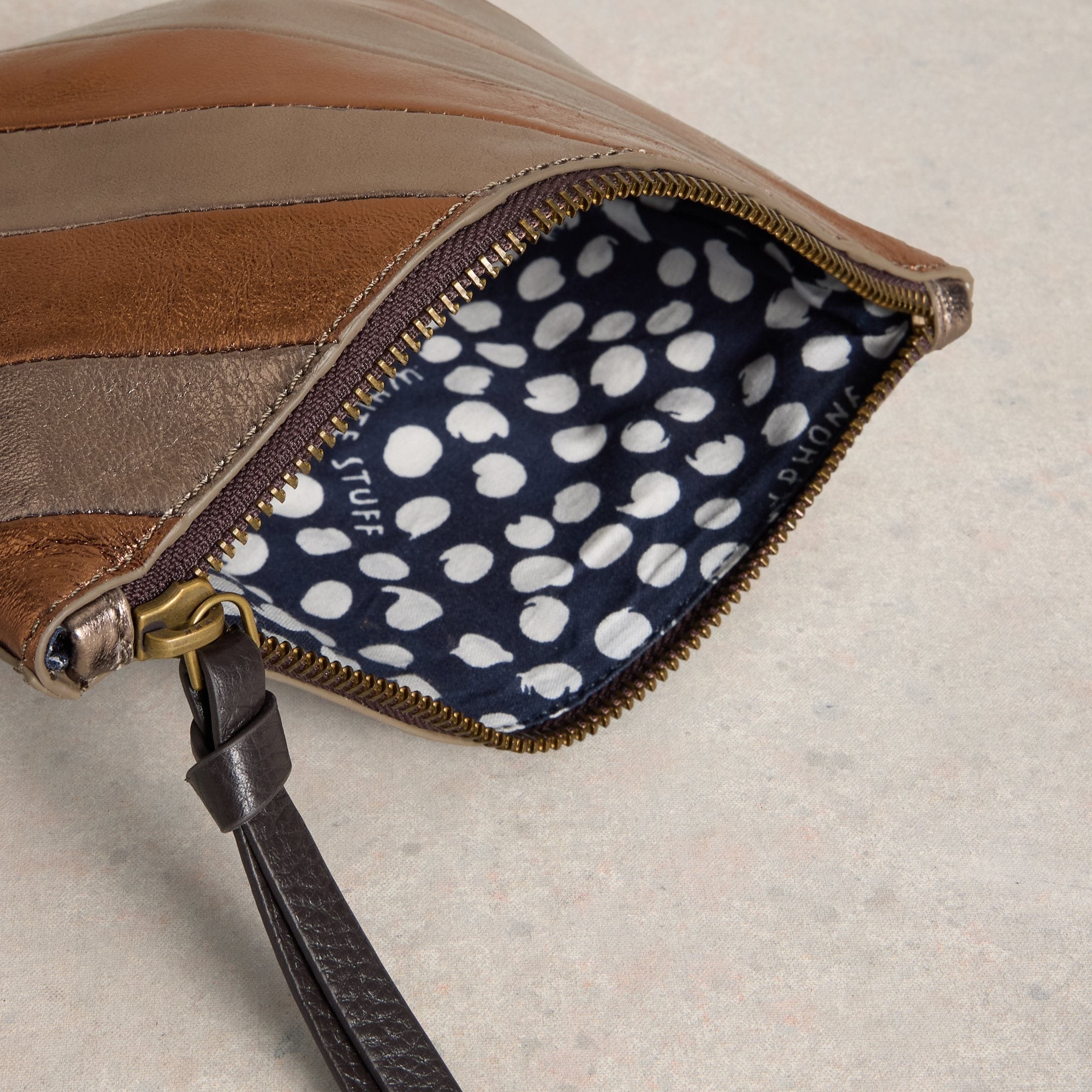 Close-up of a leather pouch with a polka dot interior on a neutral background