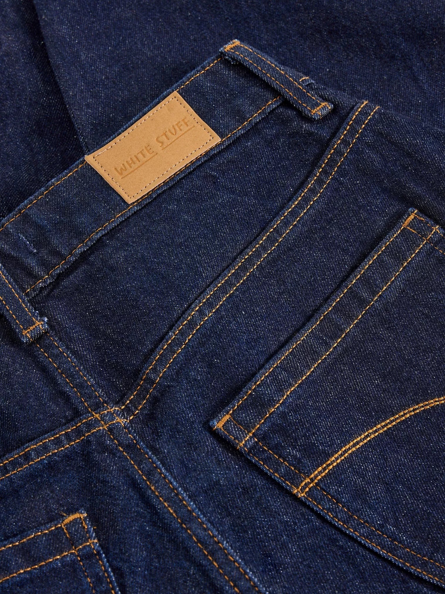 Close-up of blue denim jeans with a brand label on the pocket.