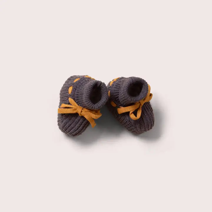 Pair of gray knitted baby booties with mustard yellow ribbon laces.