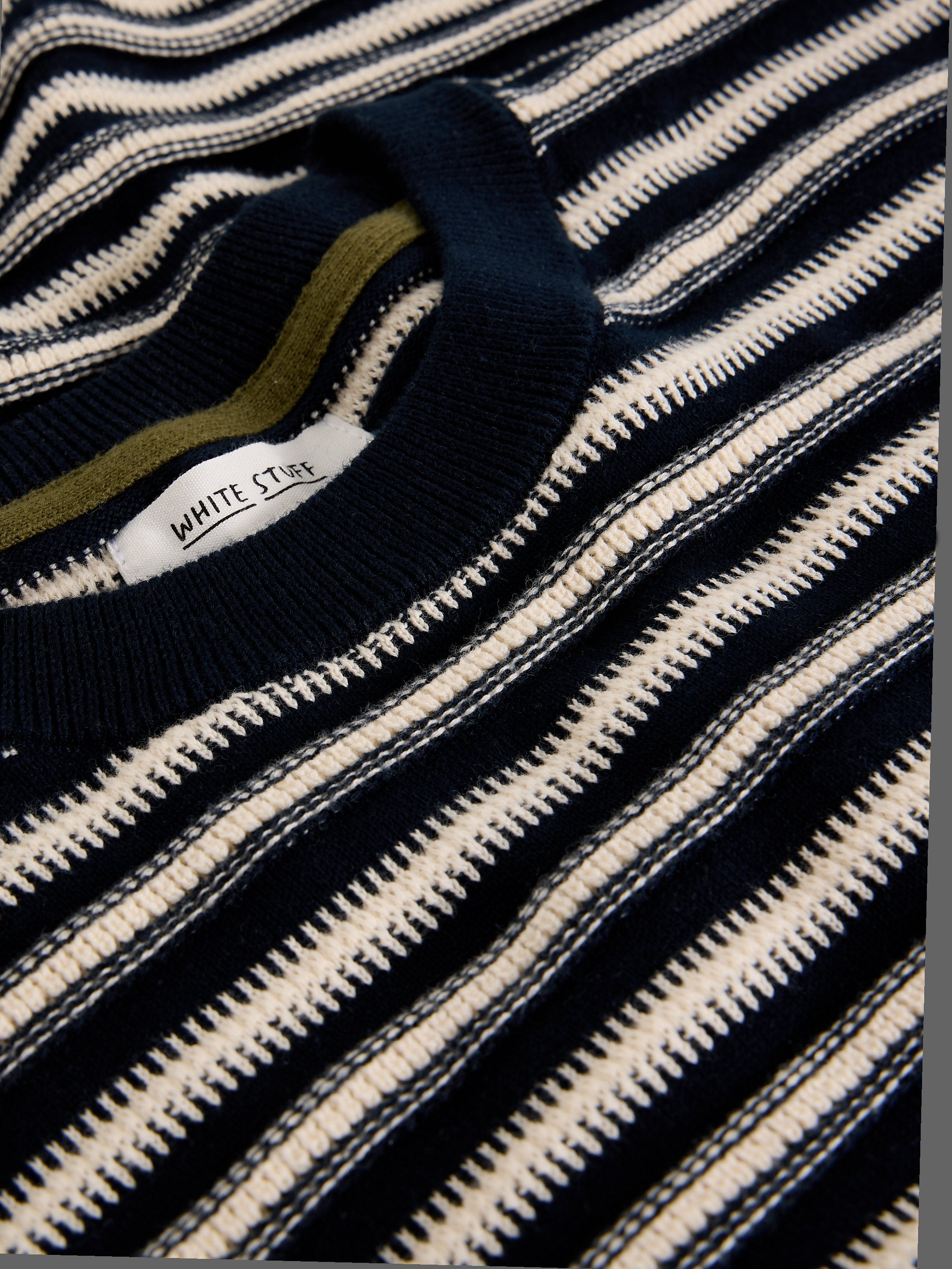 Close-up of a black and white striped sweater with 'White Stuff' label.