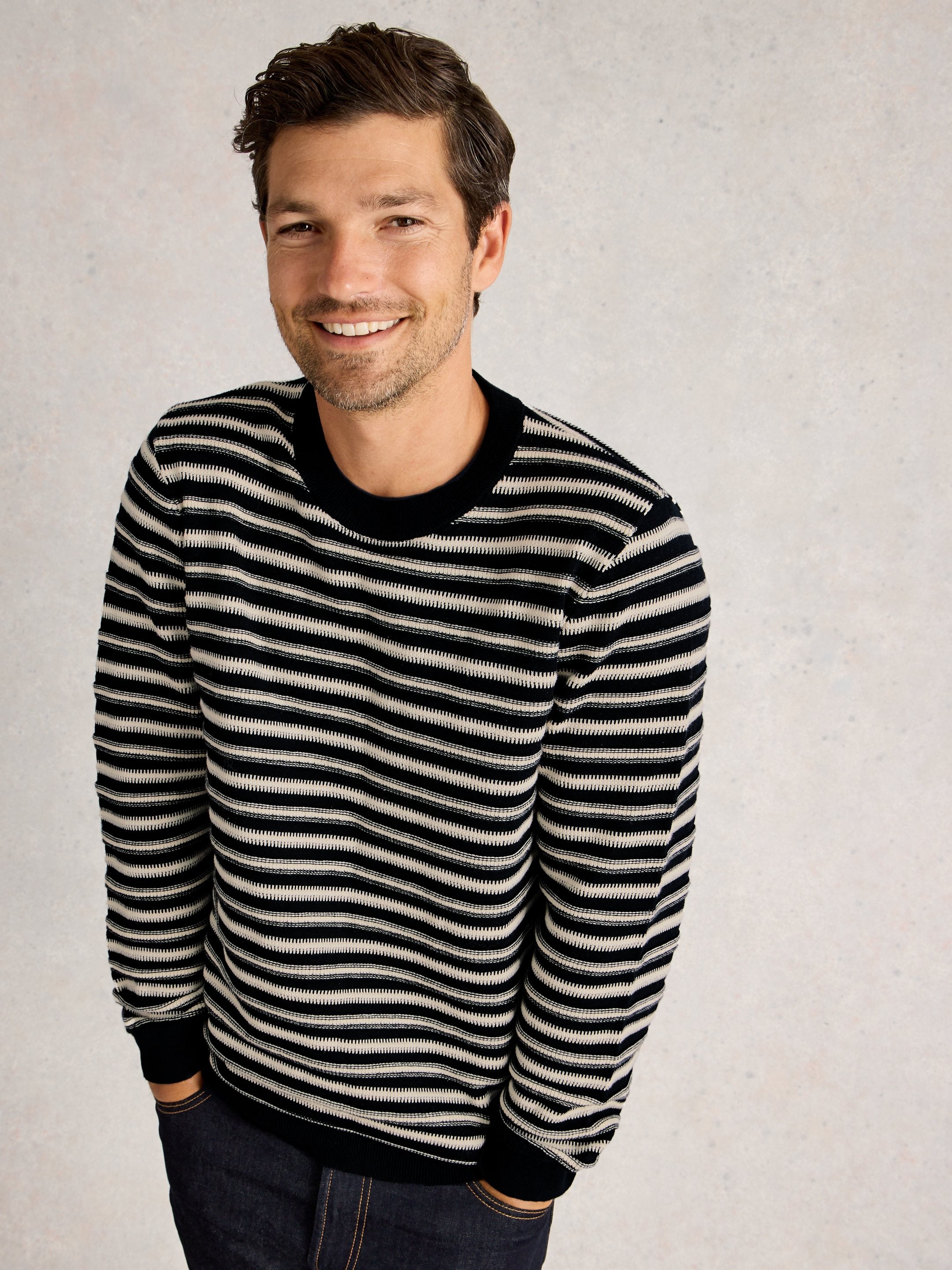 Man wearing a black and white striped sweater against a plain background