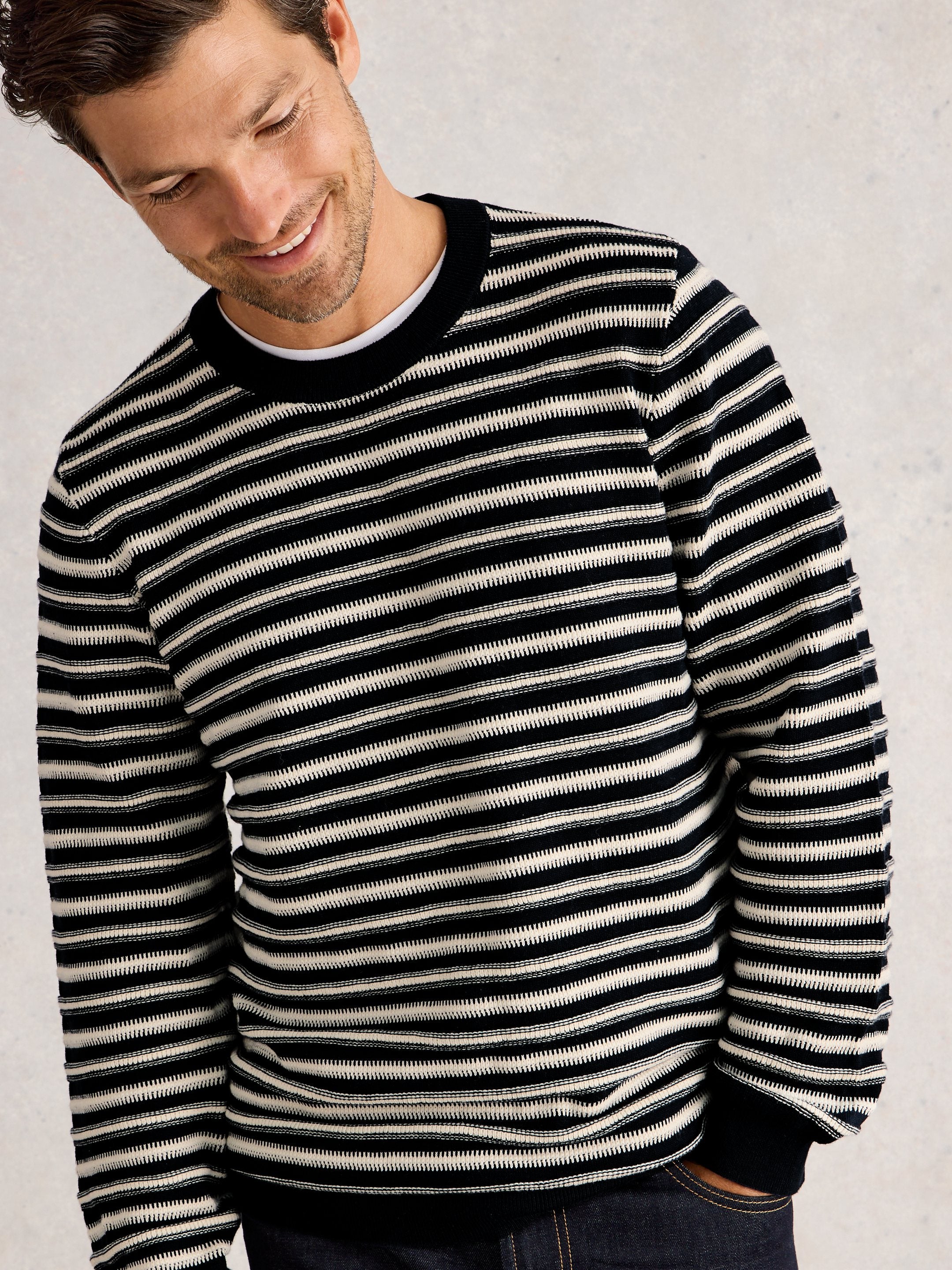 Man wearing a black and white striped sweater on a light gray background