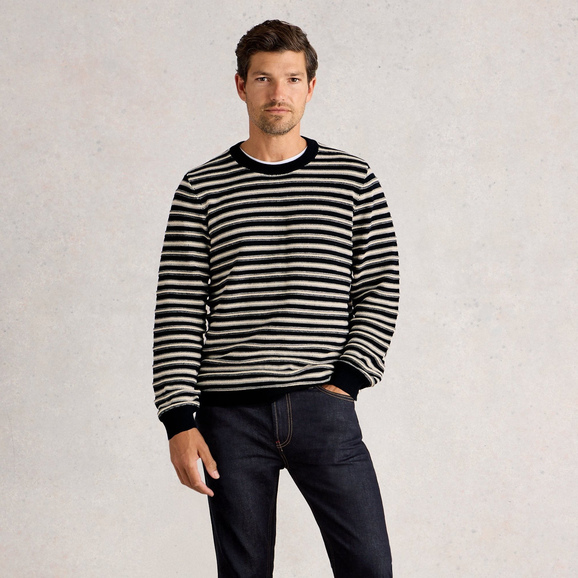 Man wearing a black and white striped sweater against a plain background