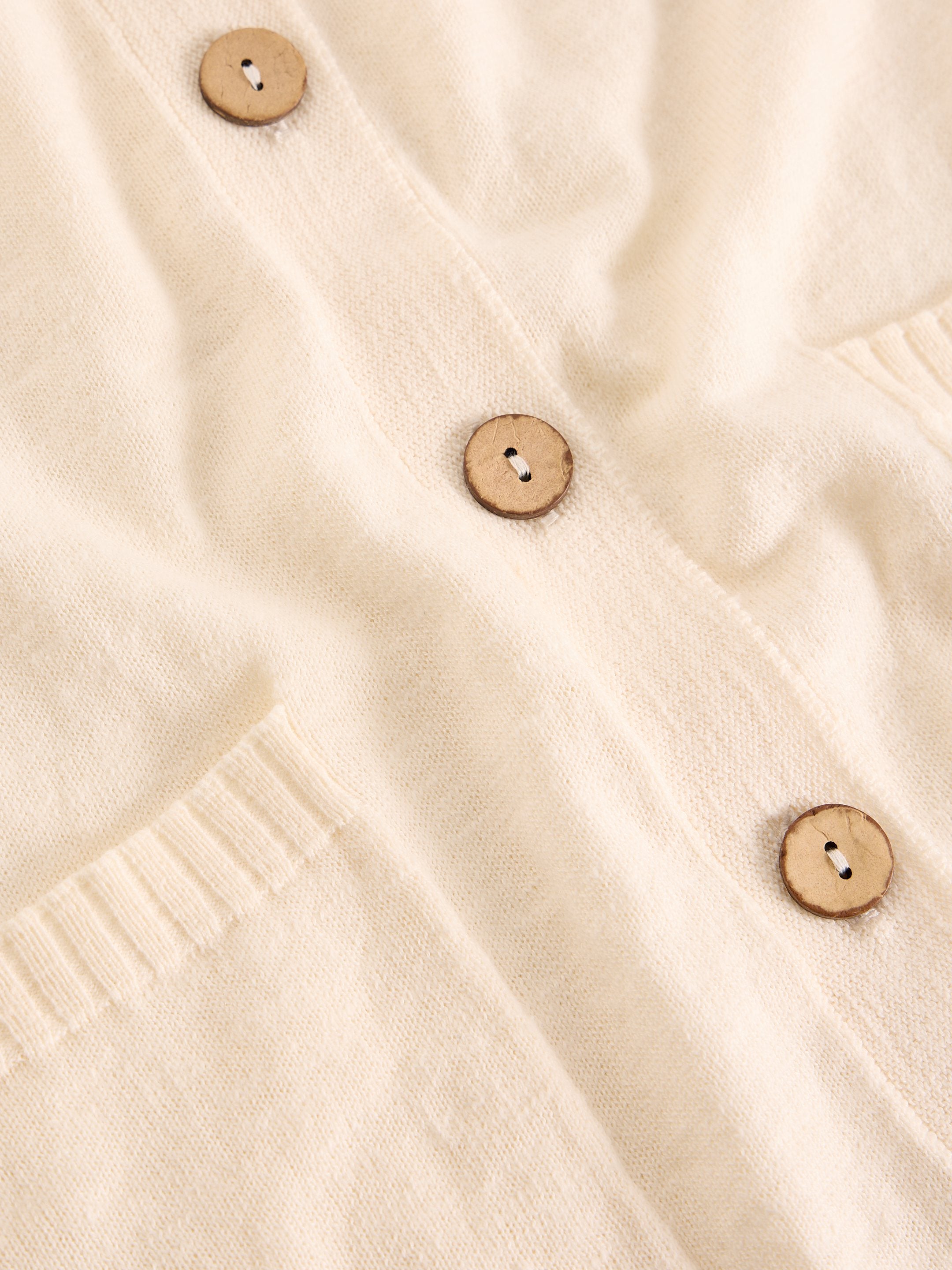 Close-up of a beige cardigan with button details