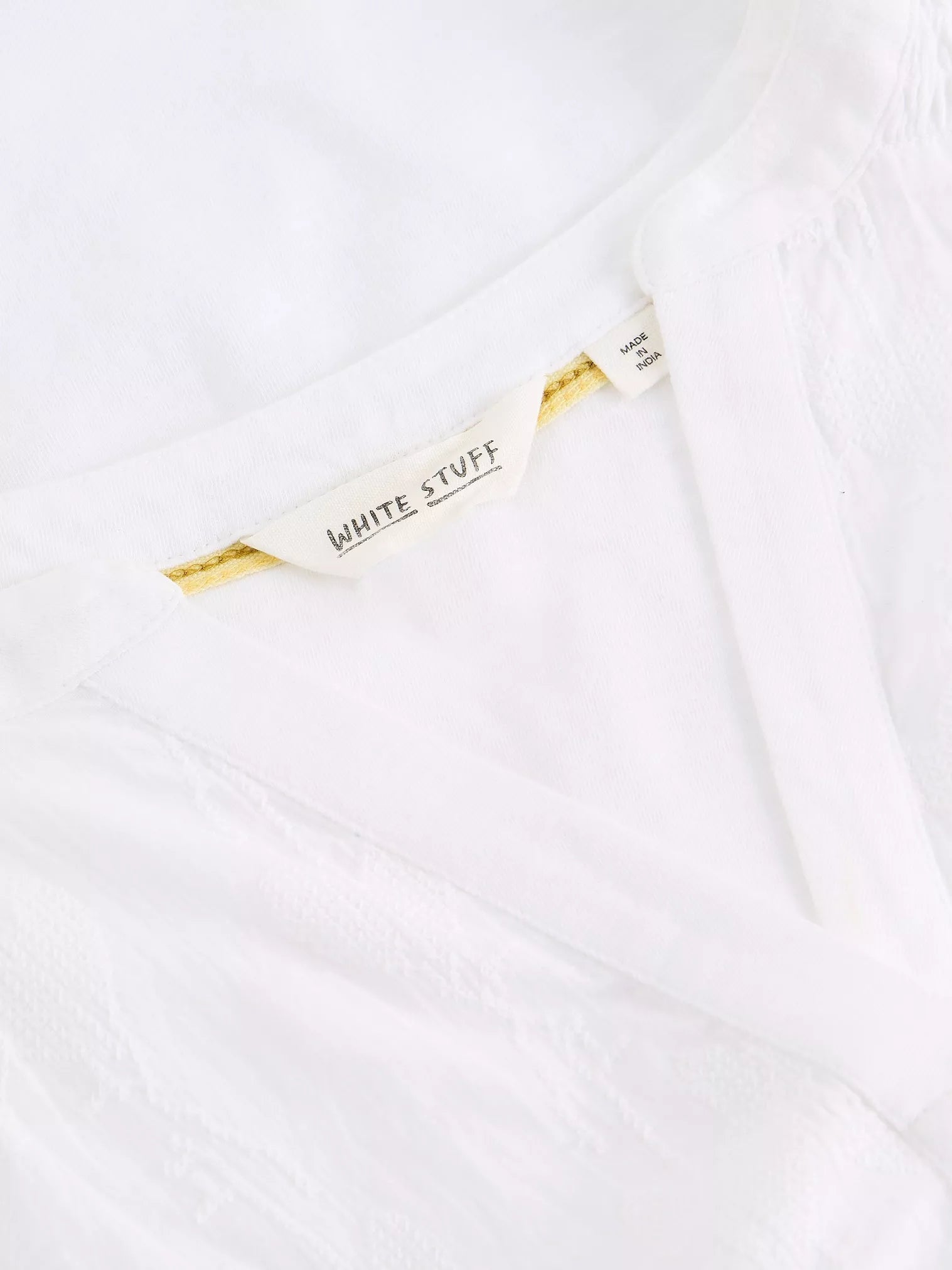Close-up of a white garment with 'White Stuff' label on a white background