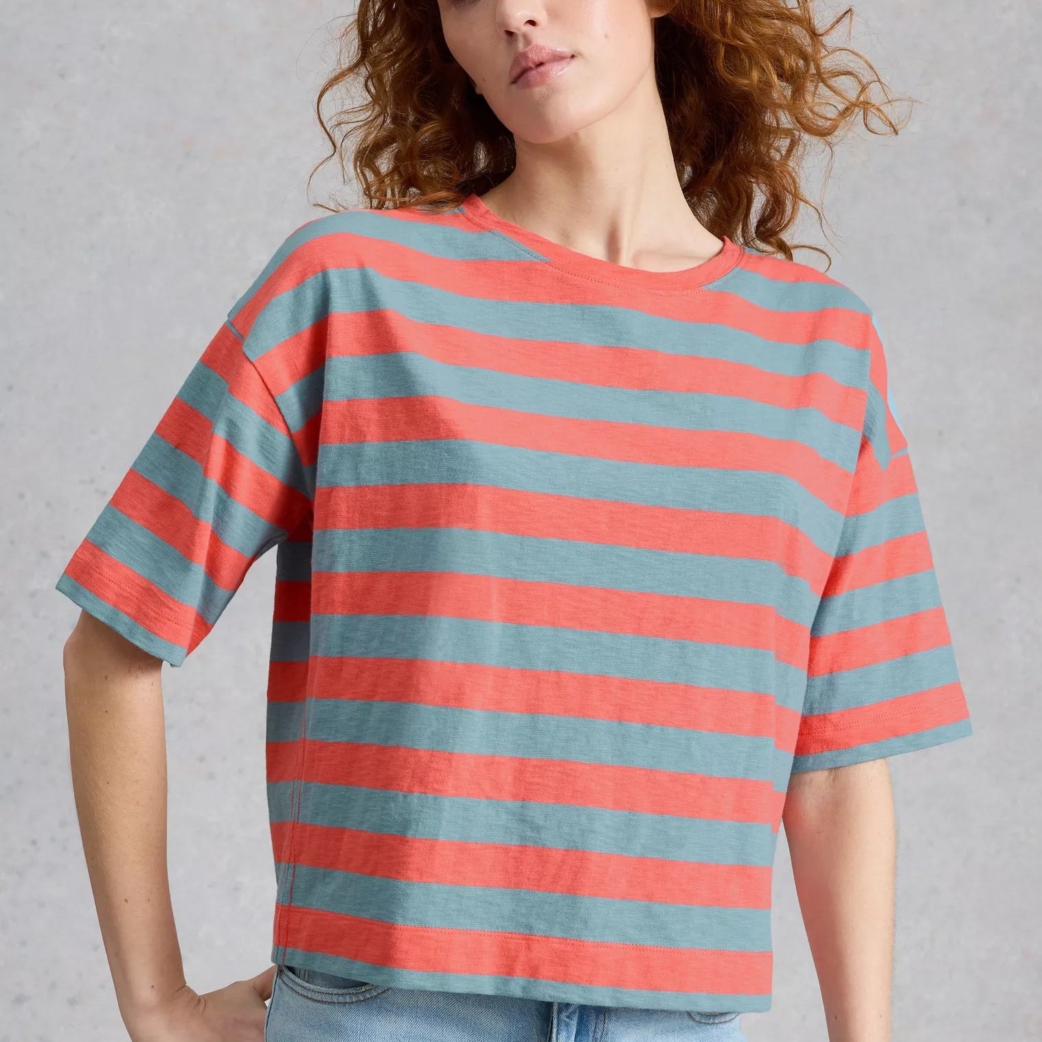 Woman wearing a red and gray striped t-shirt against a plain background