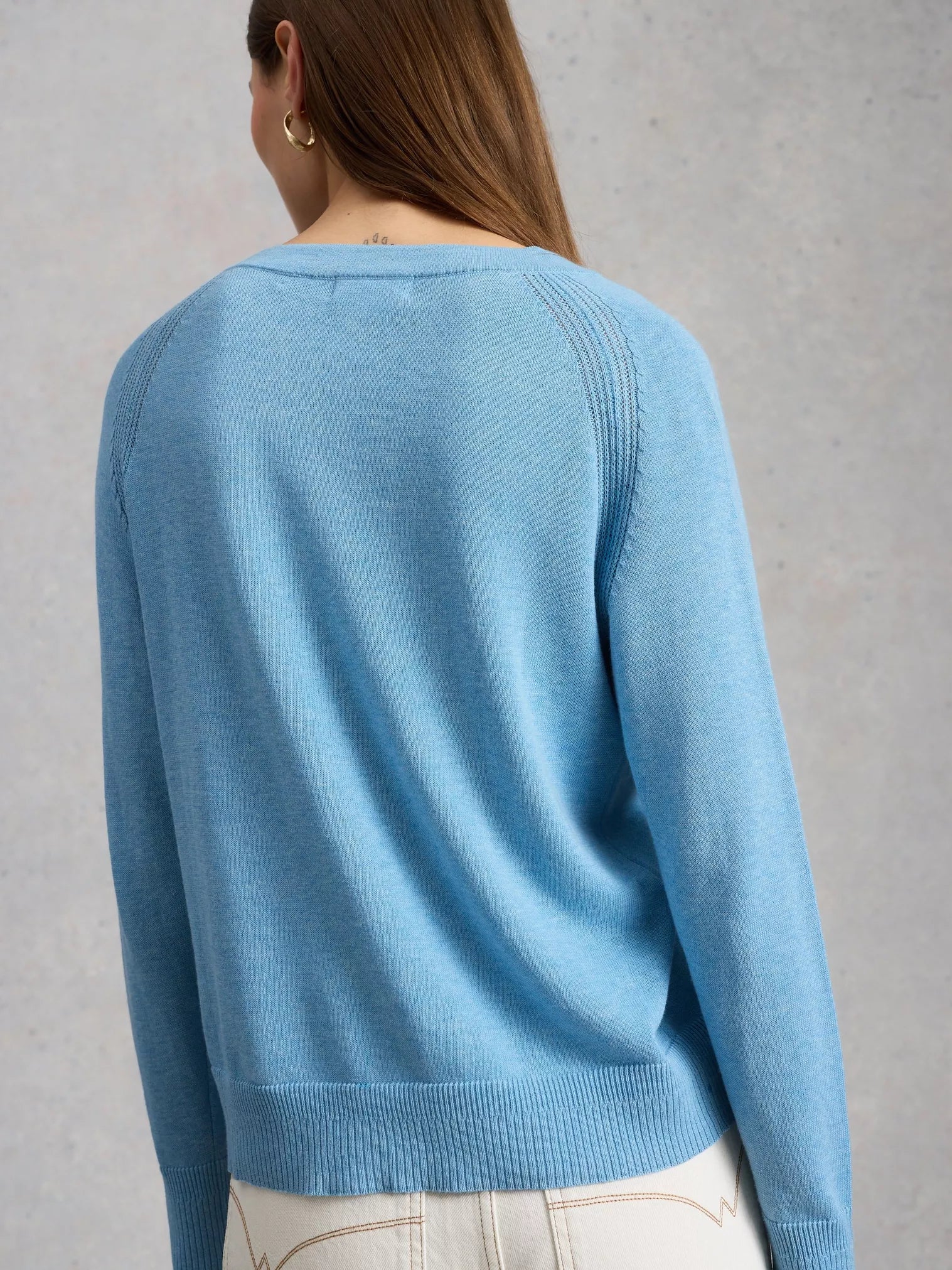 Person wearing a light blue sweater against a gray background