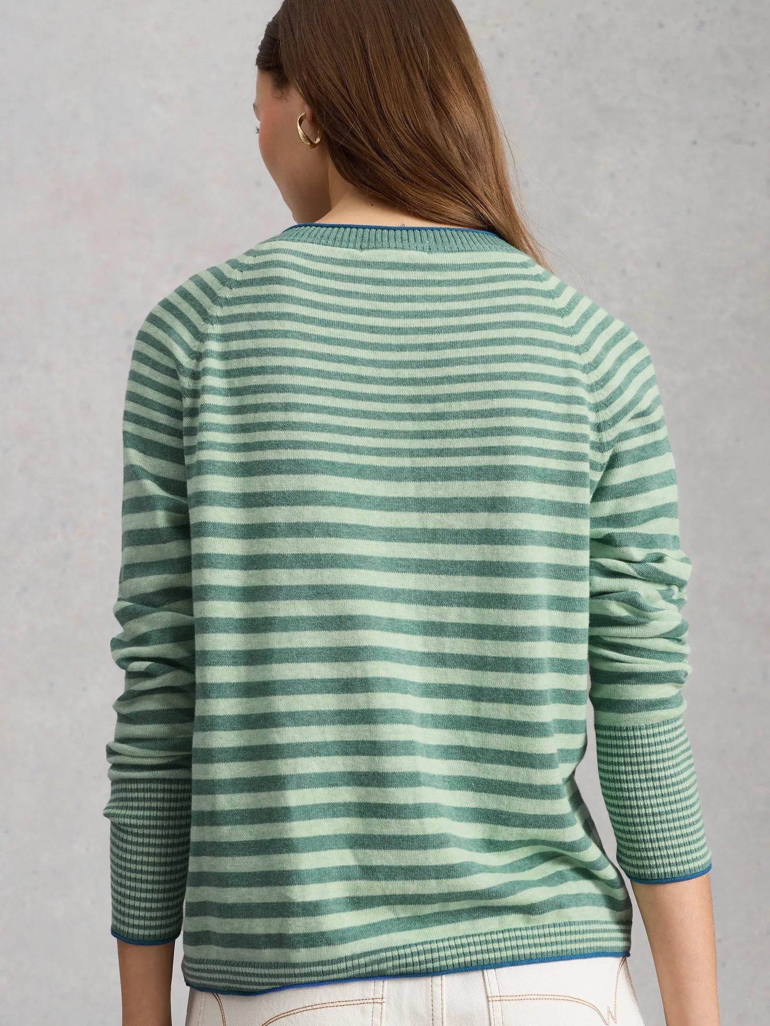 Person wearing a green and white striped sweater against a gray background