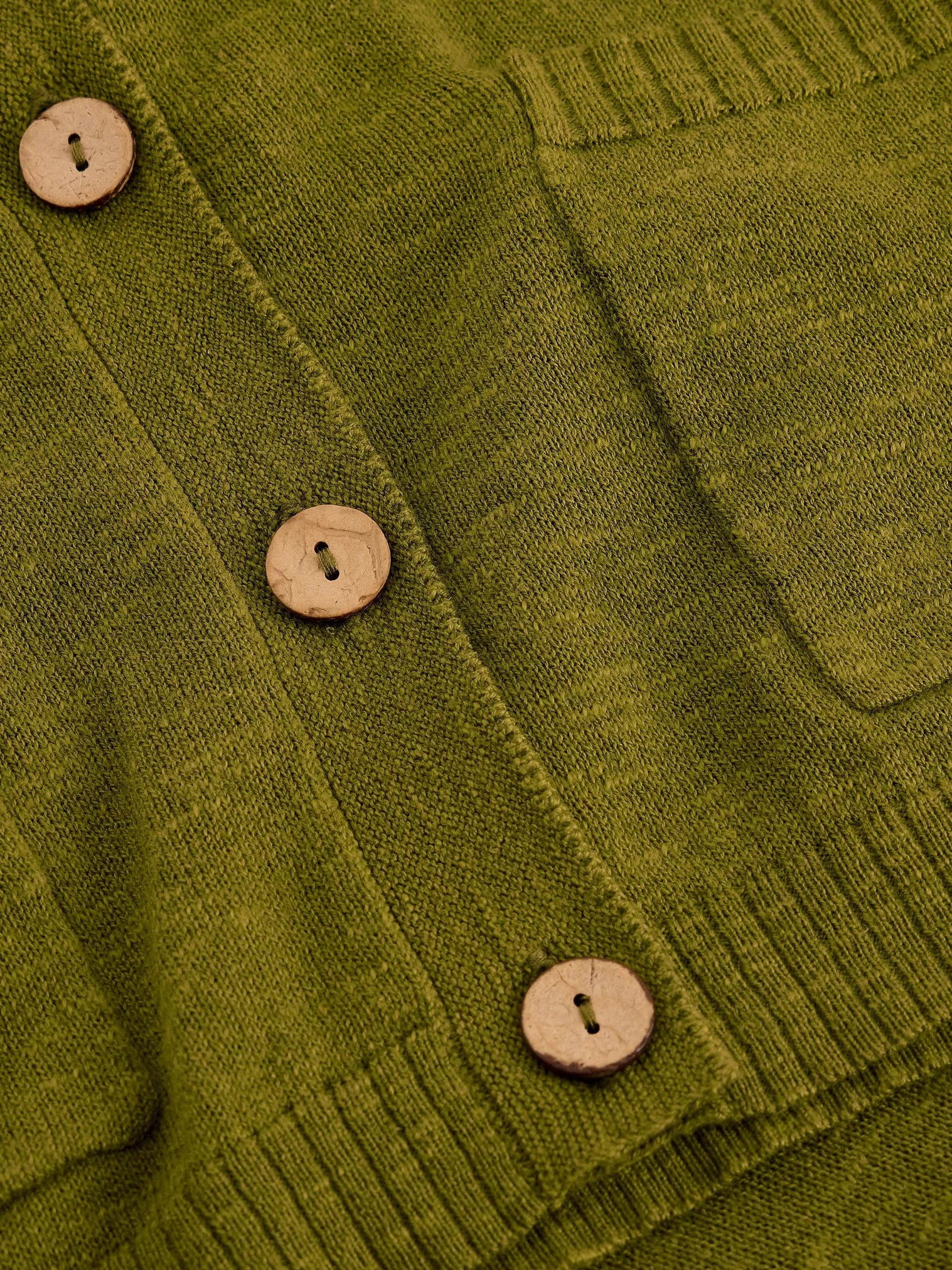 Close-up of a green knitted cardigan with wooden buttons