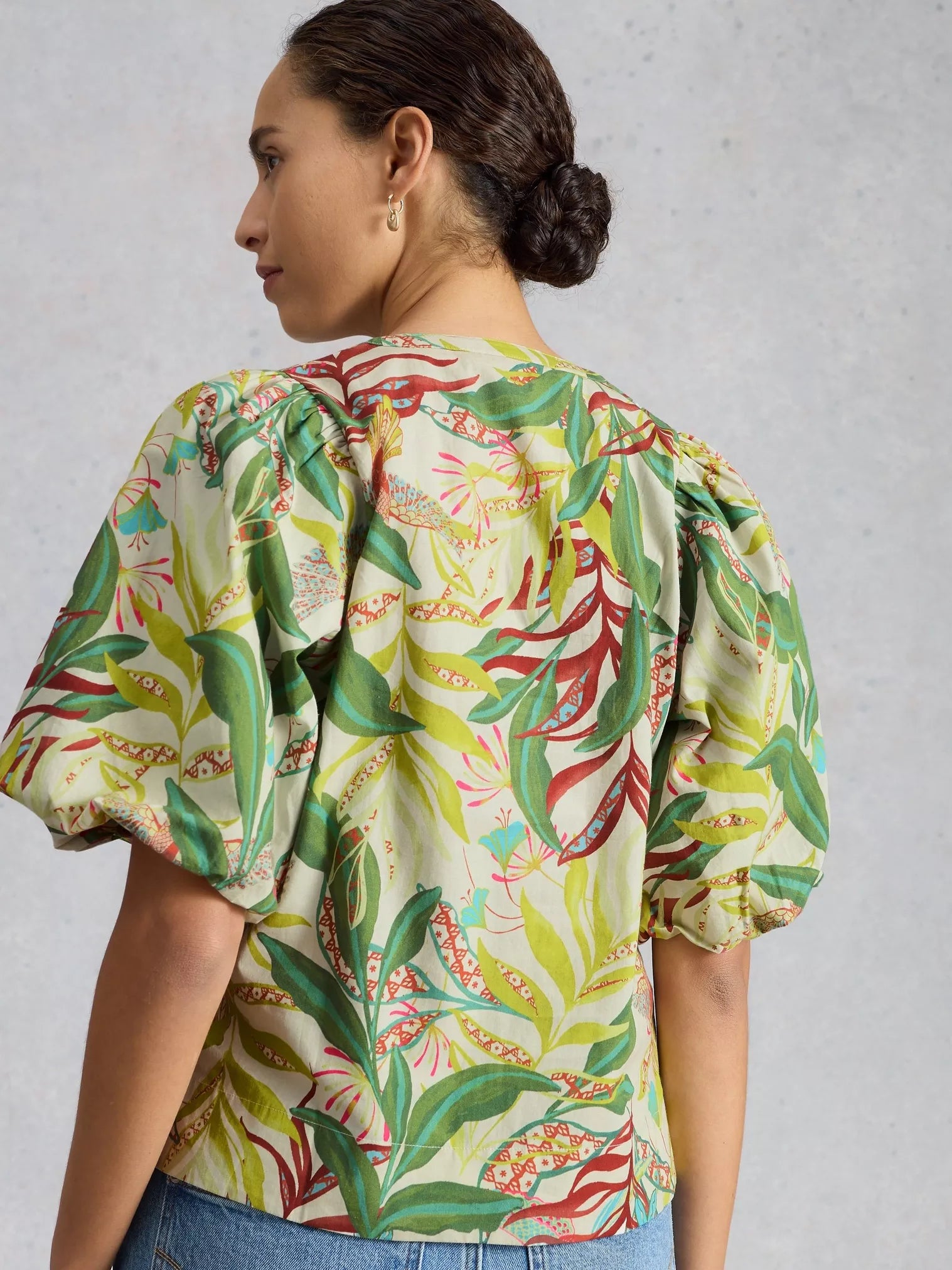 Woman wearing a colorful floral blouse against a plain background