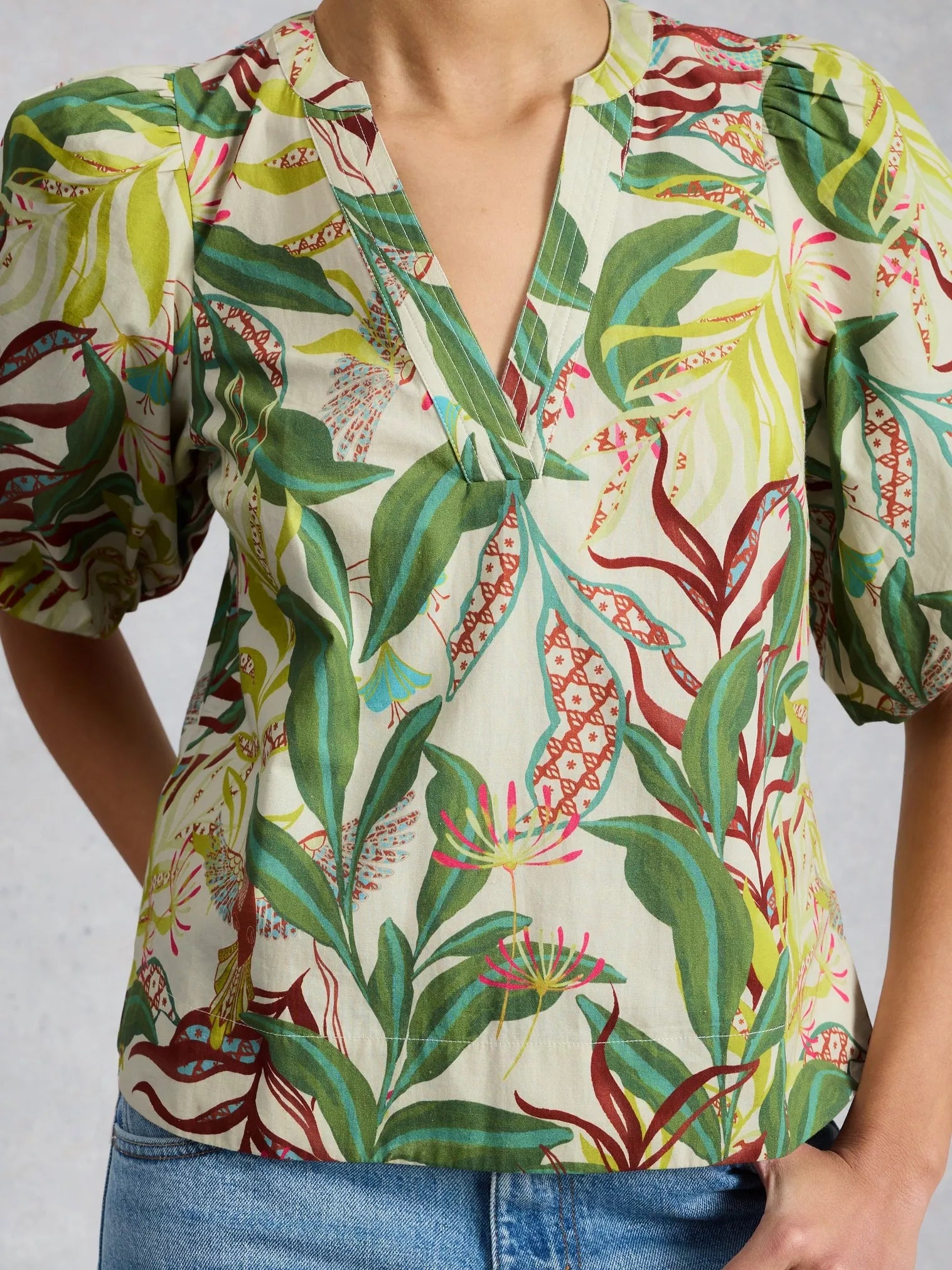 Person wearing a colorful tropical patterned shirt with a plain background