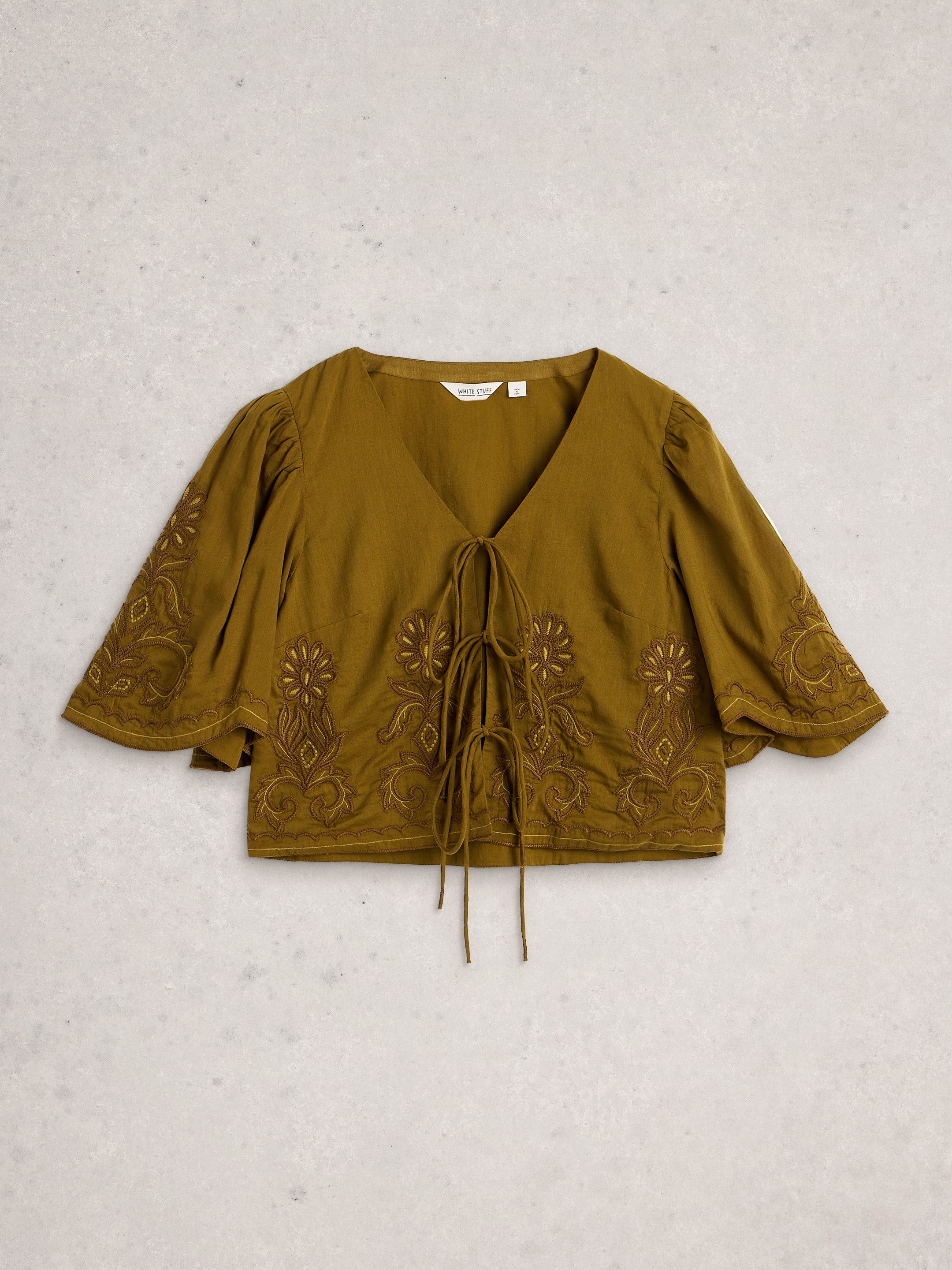 Green blouse with floral embroidery on a light gray background