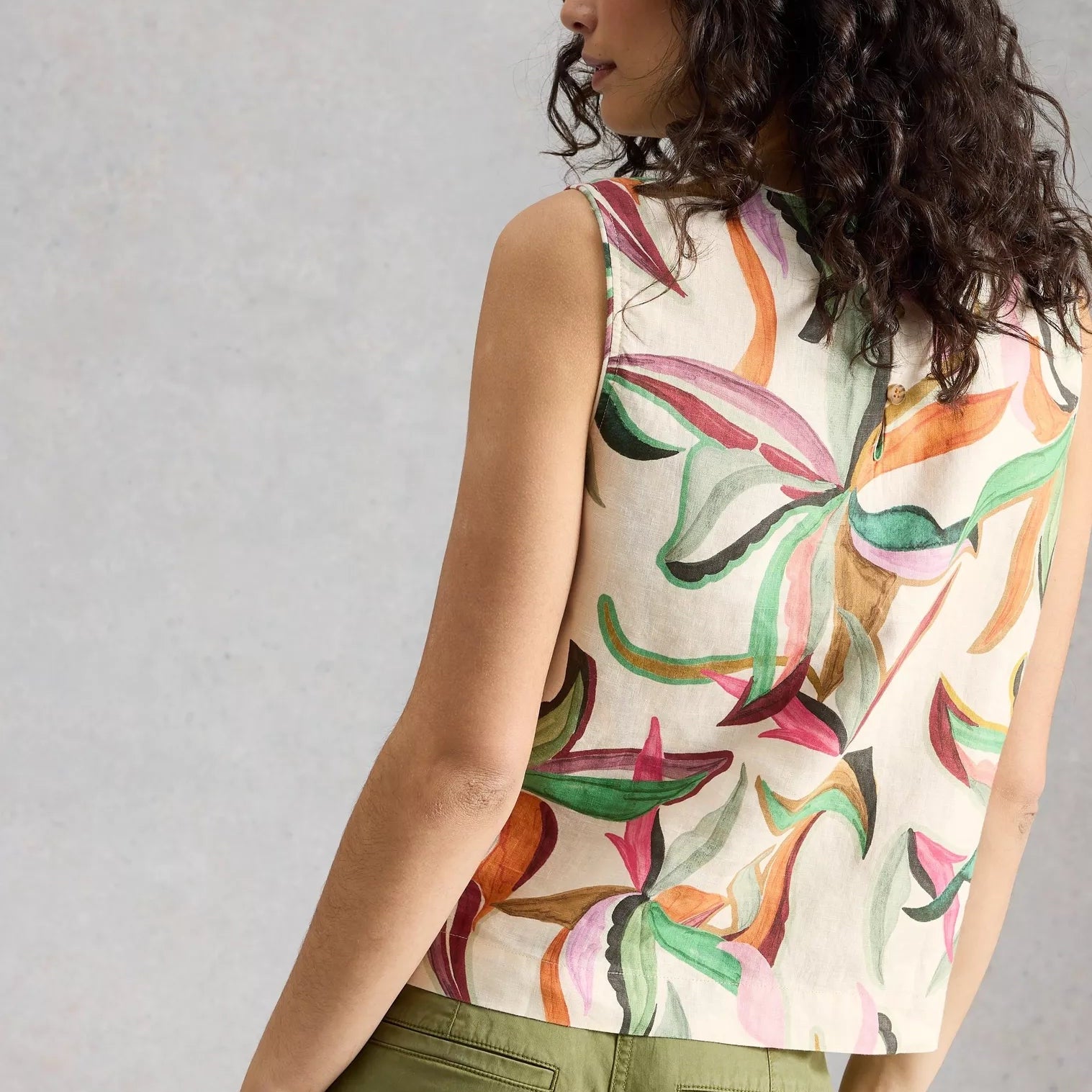 Woman wearing a sleeveless top with colorful leaf pattern against a plain background