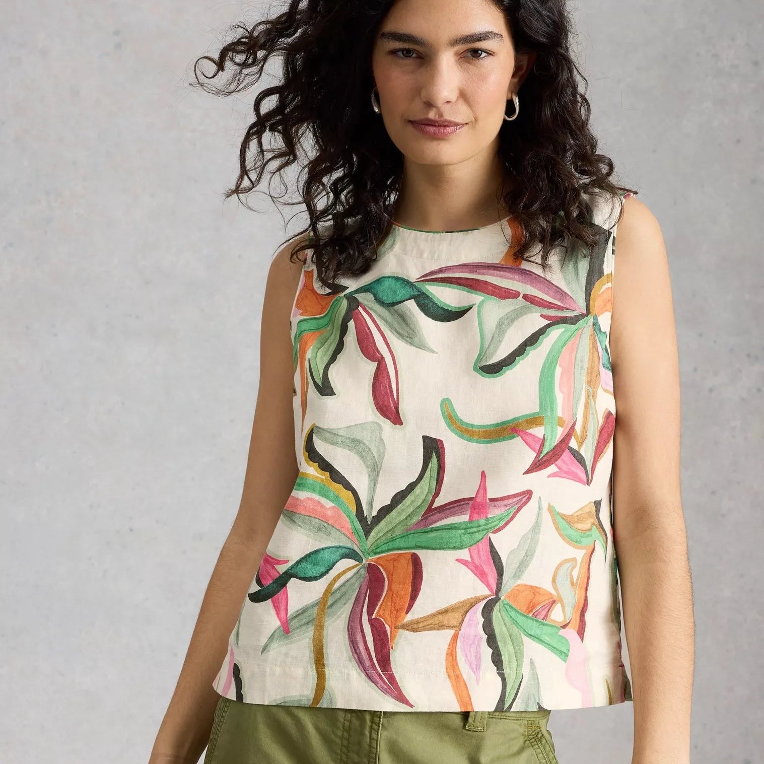 Woman wearing a sleeveless top with colorful leaf pattern against a plain background