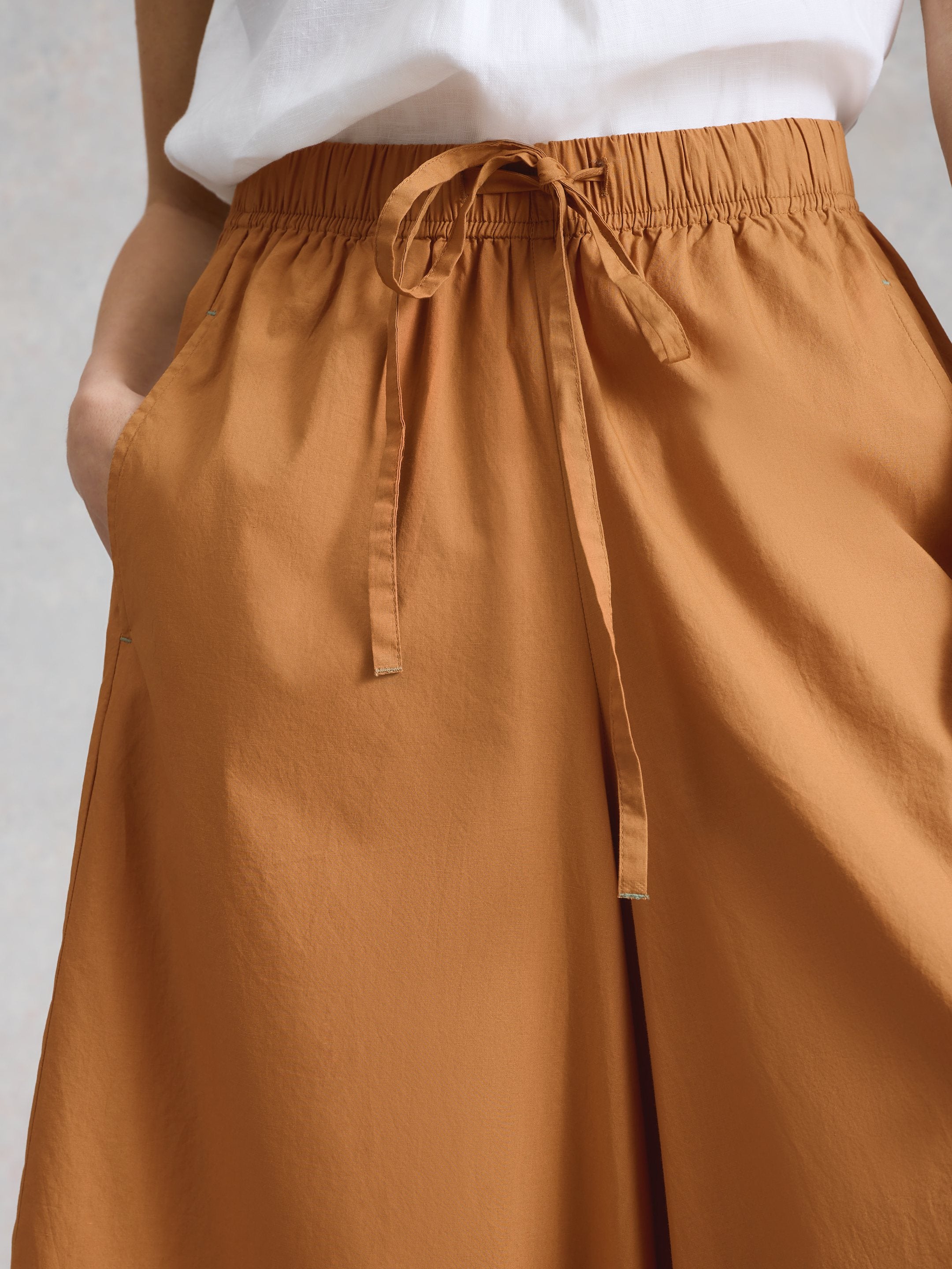 Brown pants with a tie waist on a plain background