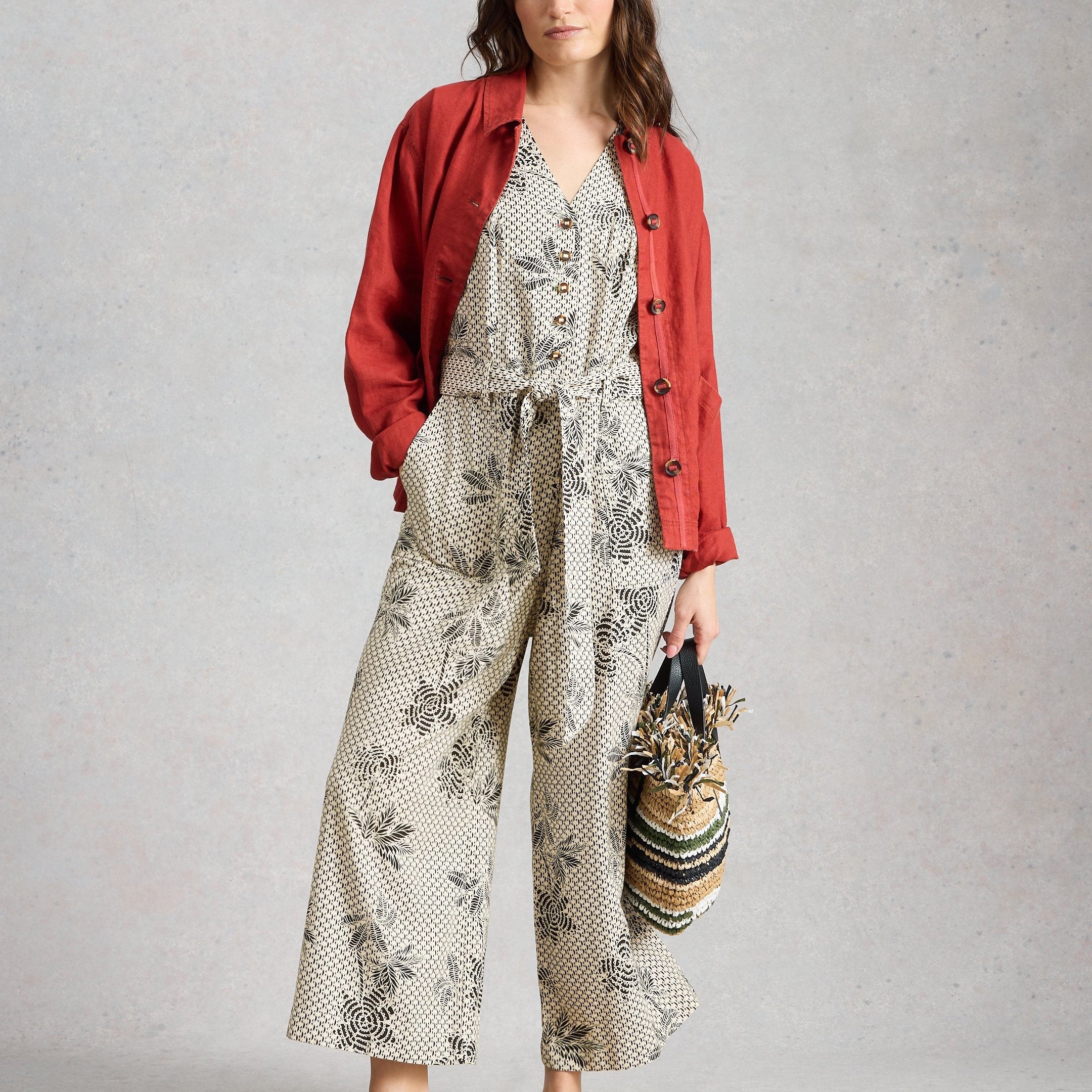 Woman wearing a floral dress with a red jacket on a gray background