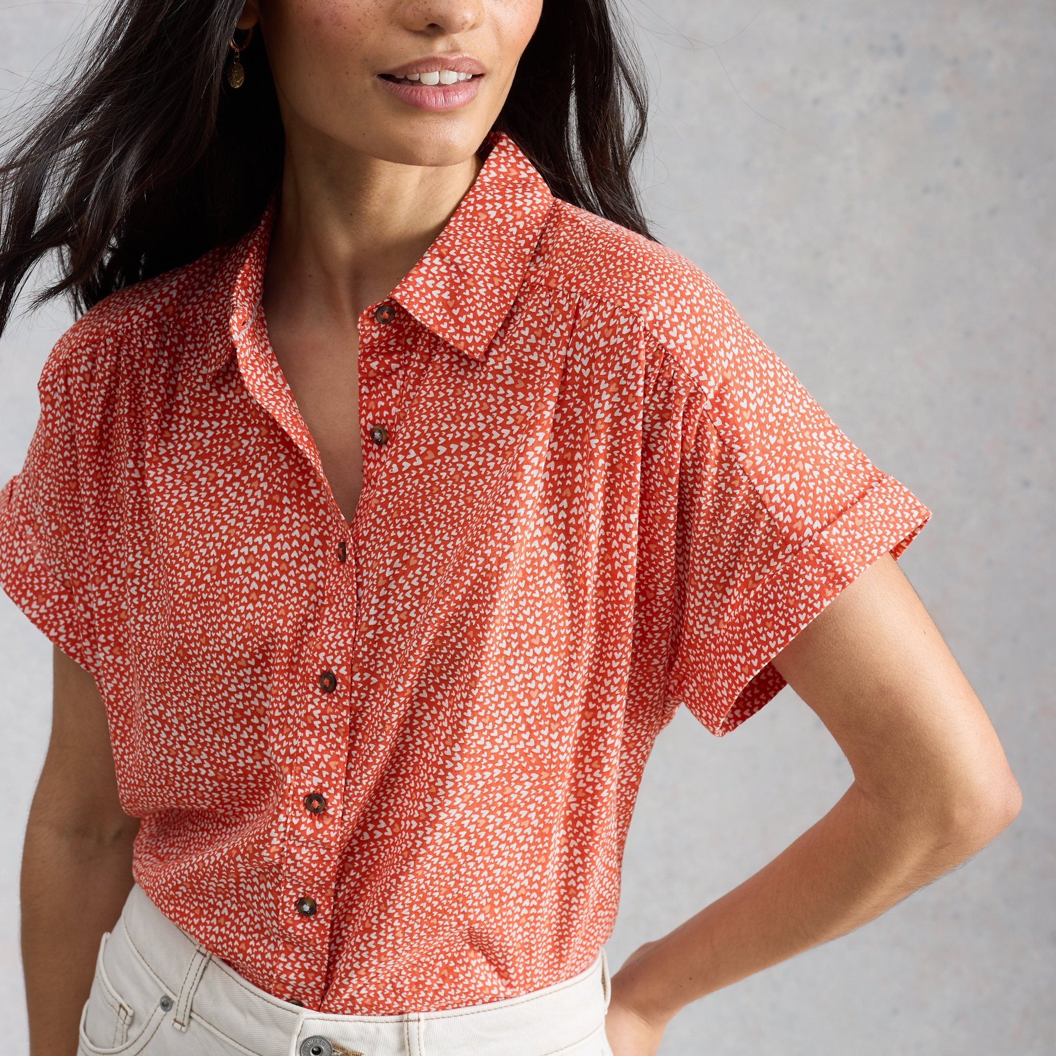 Woman wearing a red patterned shirt against a gray background