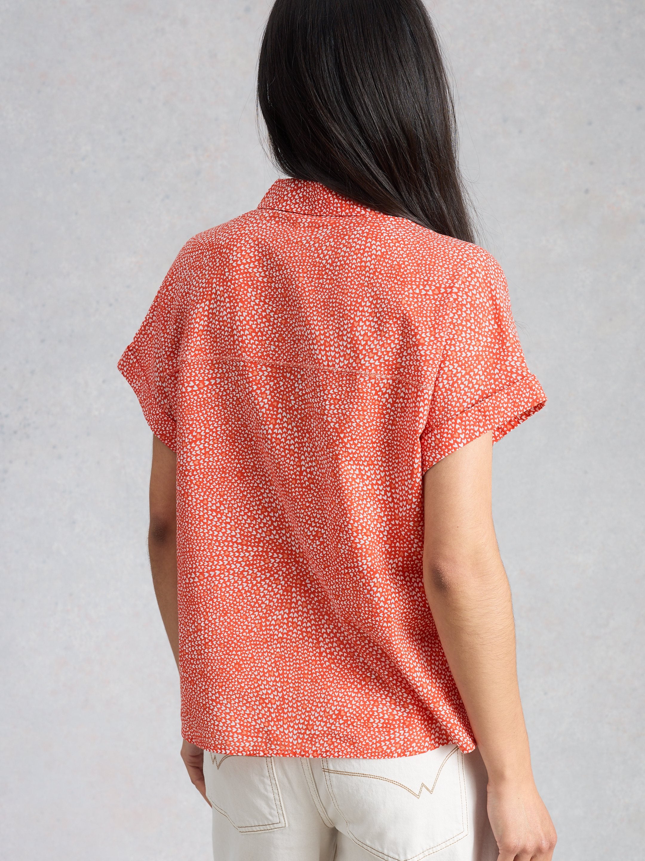 Person wearing a red patterned shirt against a gray background