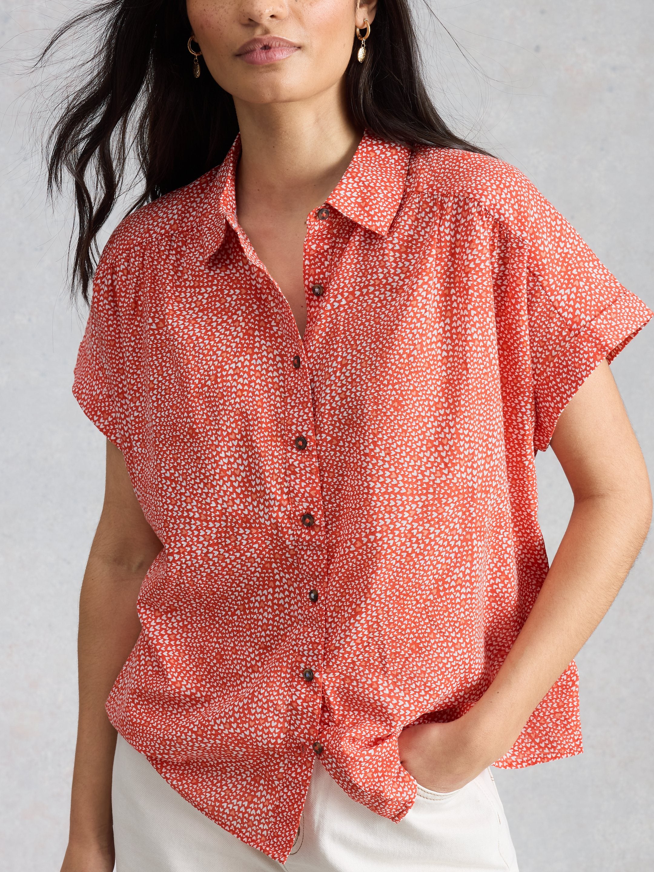 Woman wearing a red patterned shirt against a gray background