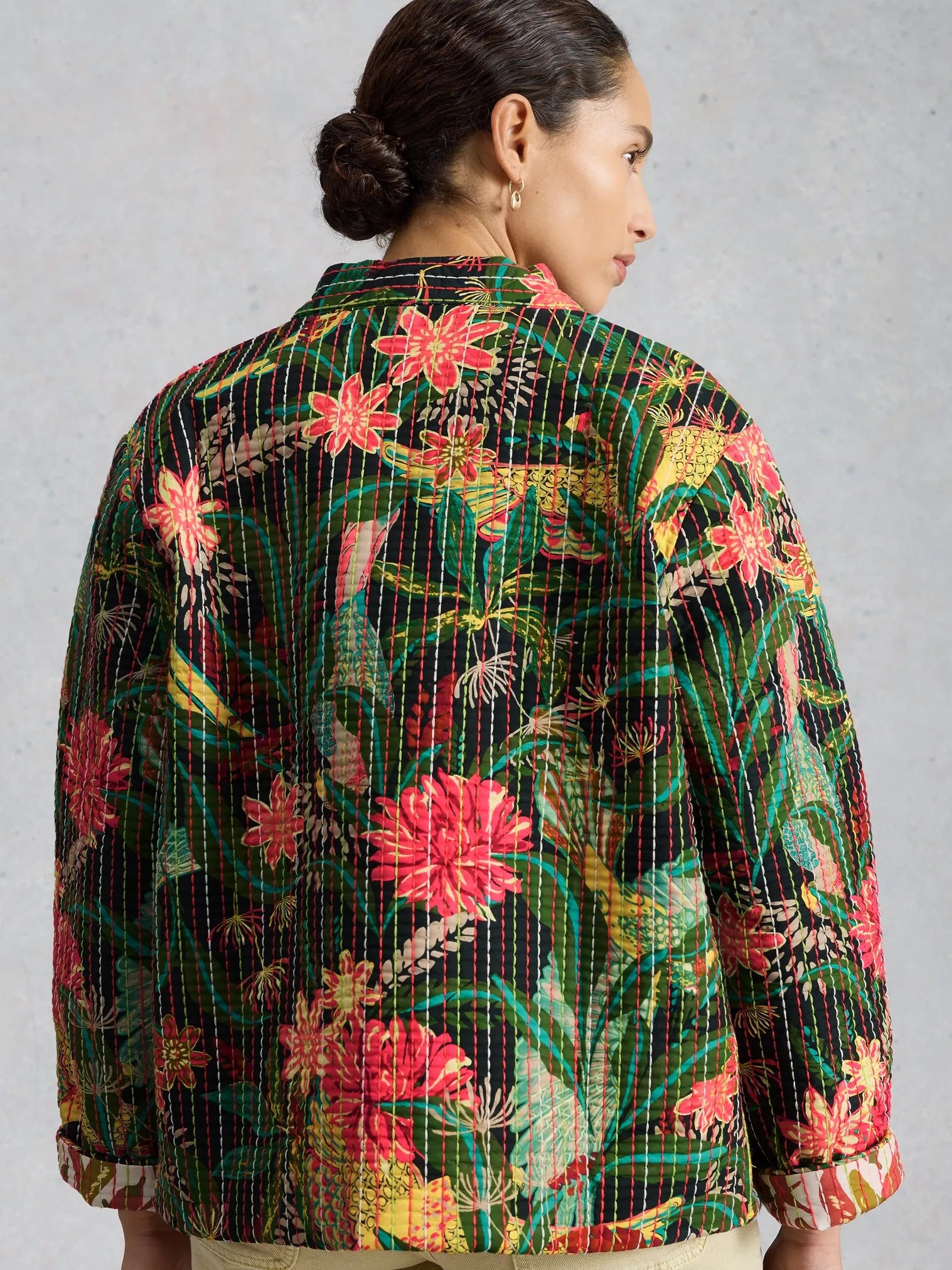 Woman wearing a colorful floral patterned shirt against a gray background