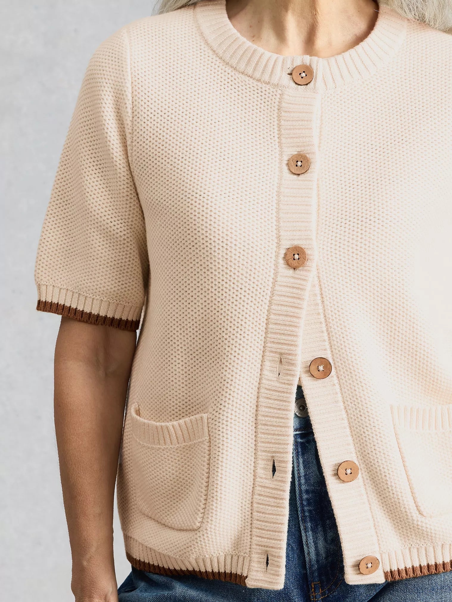 Beige cardigan with brown buttons on a neutral background