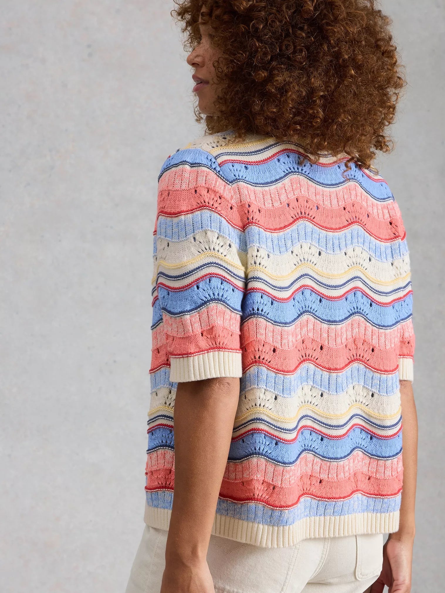 Person wearing a colorful striped sweater against a plain background