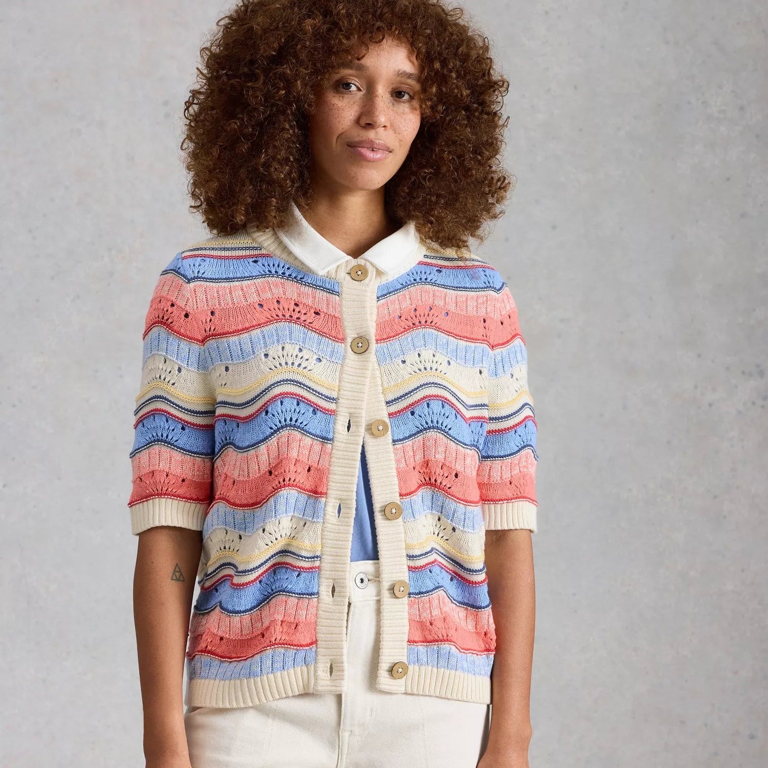 Woman wearing a colorful striped cardigan against a gray background