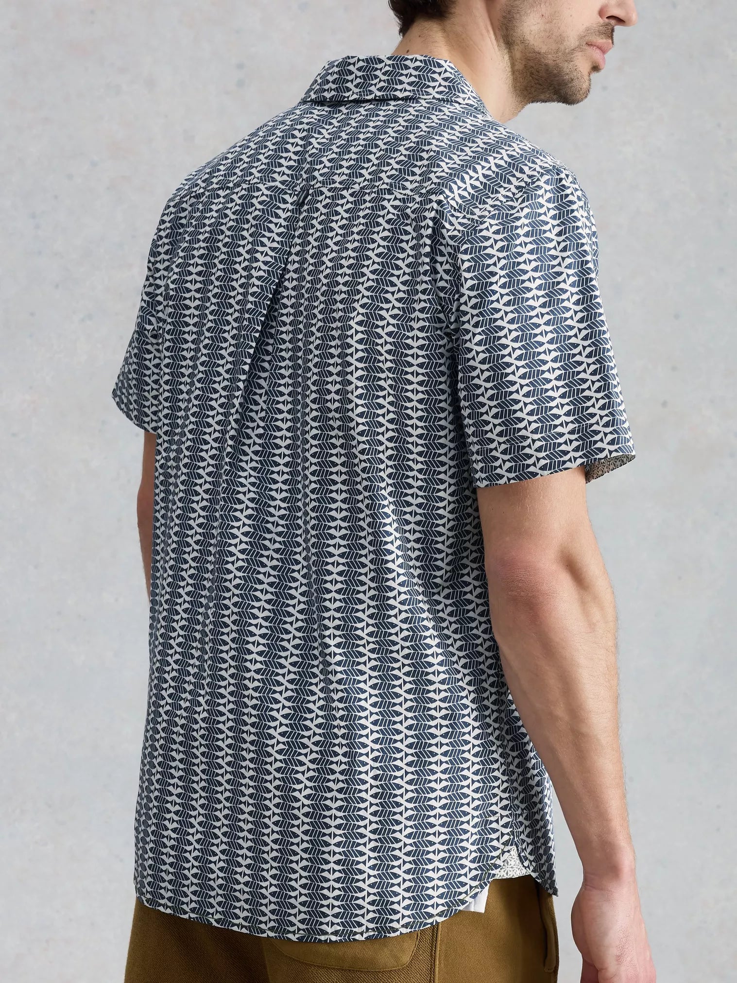 Man wearing a patterned short-sleeve shirt against a plain background