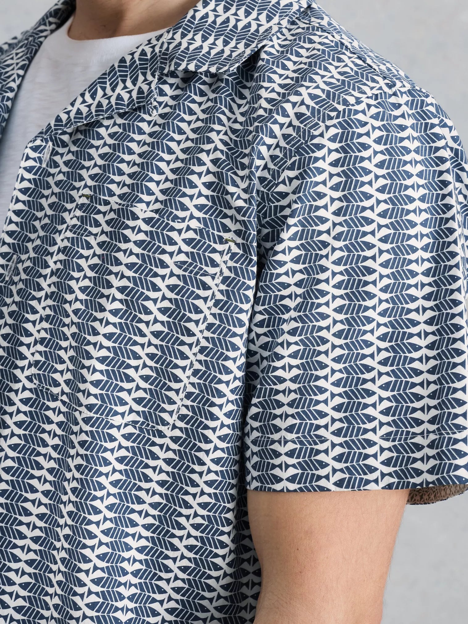 Close-up of a person wearing a patterned shirt with blue and white geometric design.