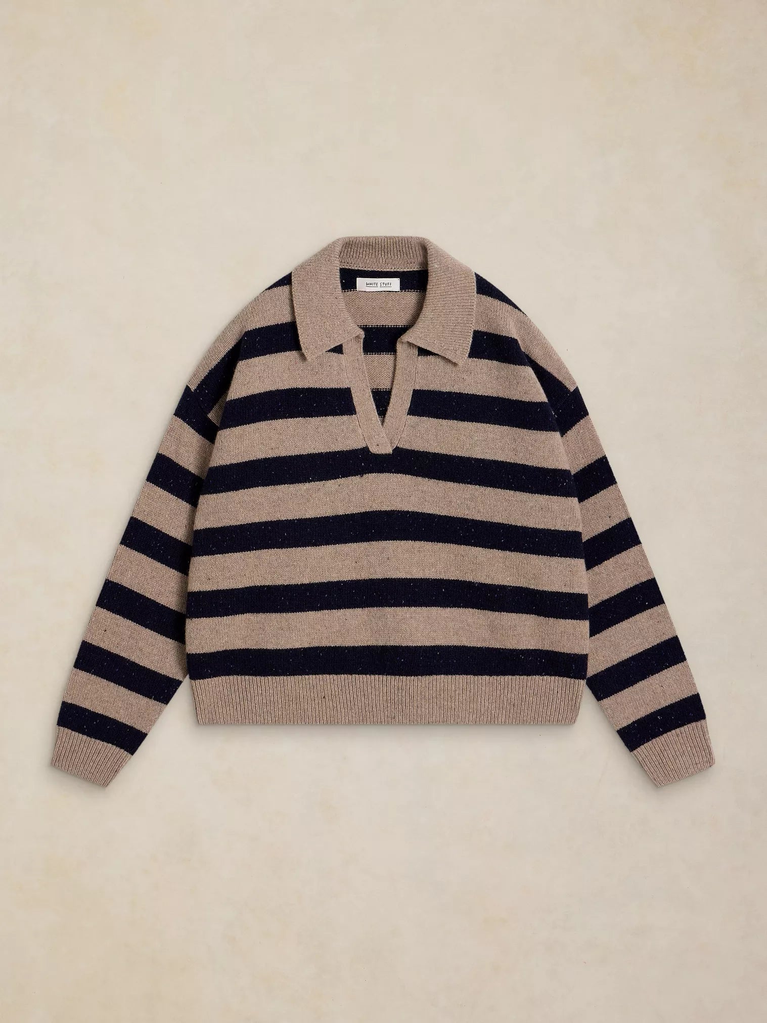 A knit polo sweater with horizontal beige and navy stripes, laid flat on a textured beige background.