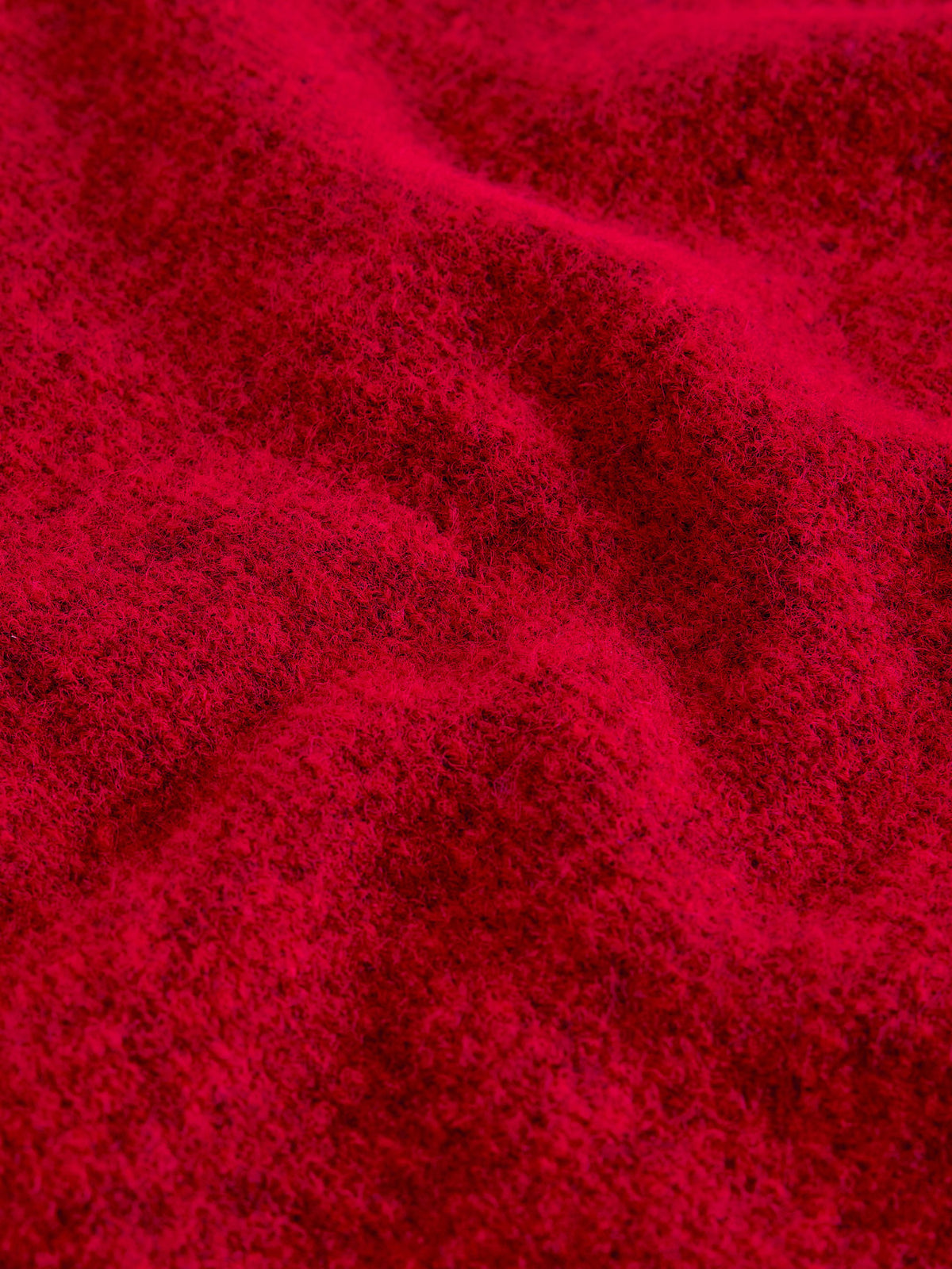 A close-up of bright red textured fabric with soft folds and a slightly fuzzy surface.