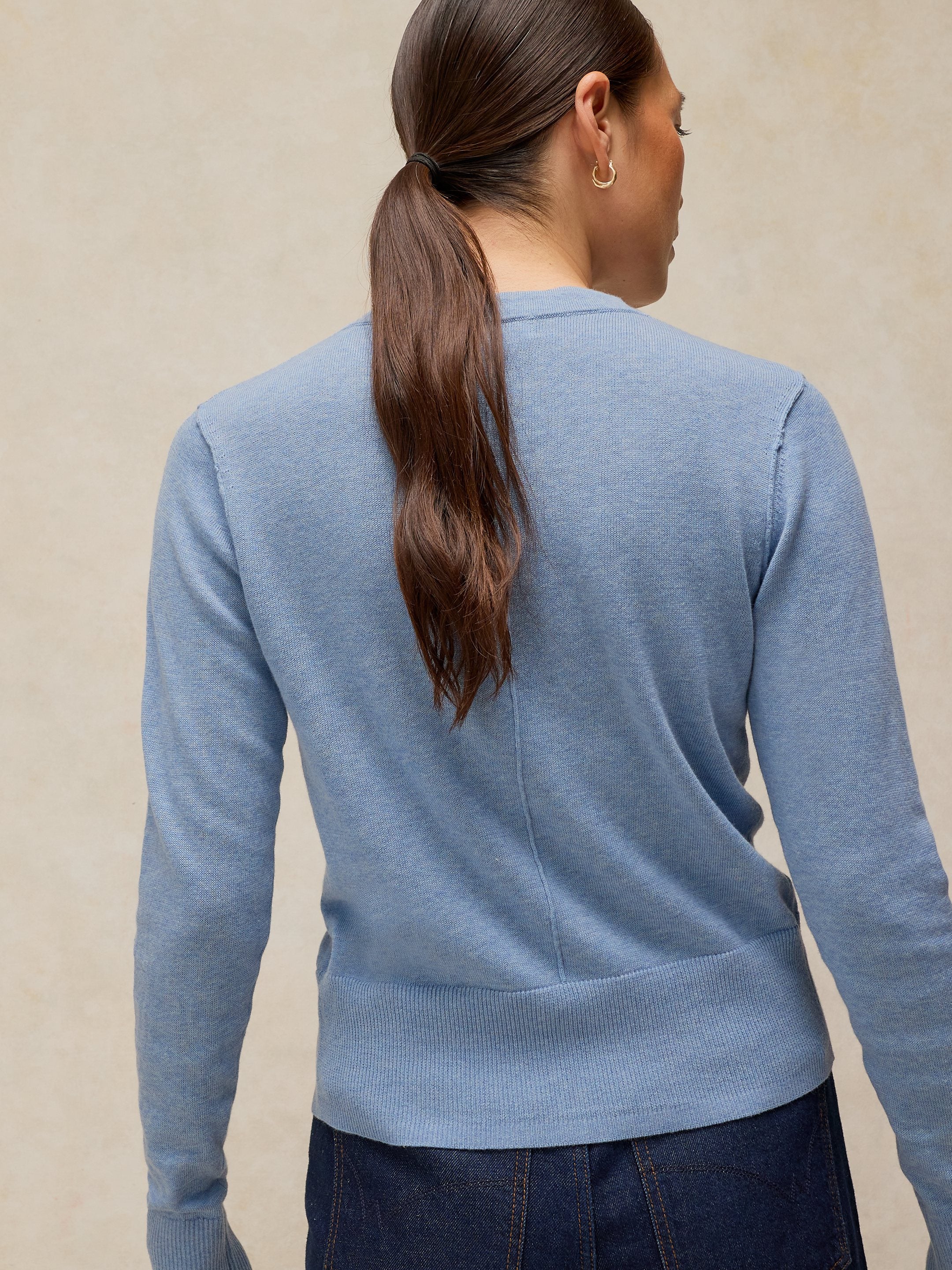 Person wearing a light blue cardigan against a beige background