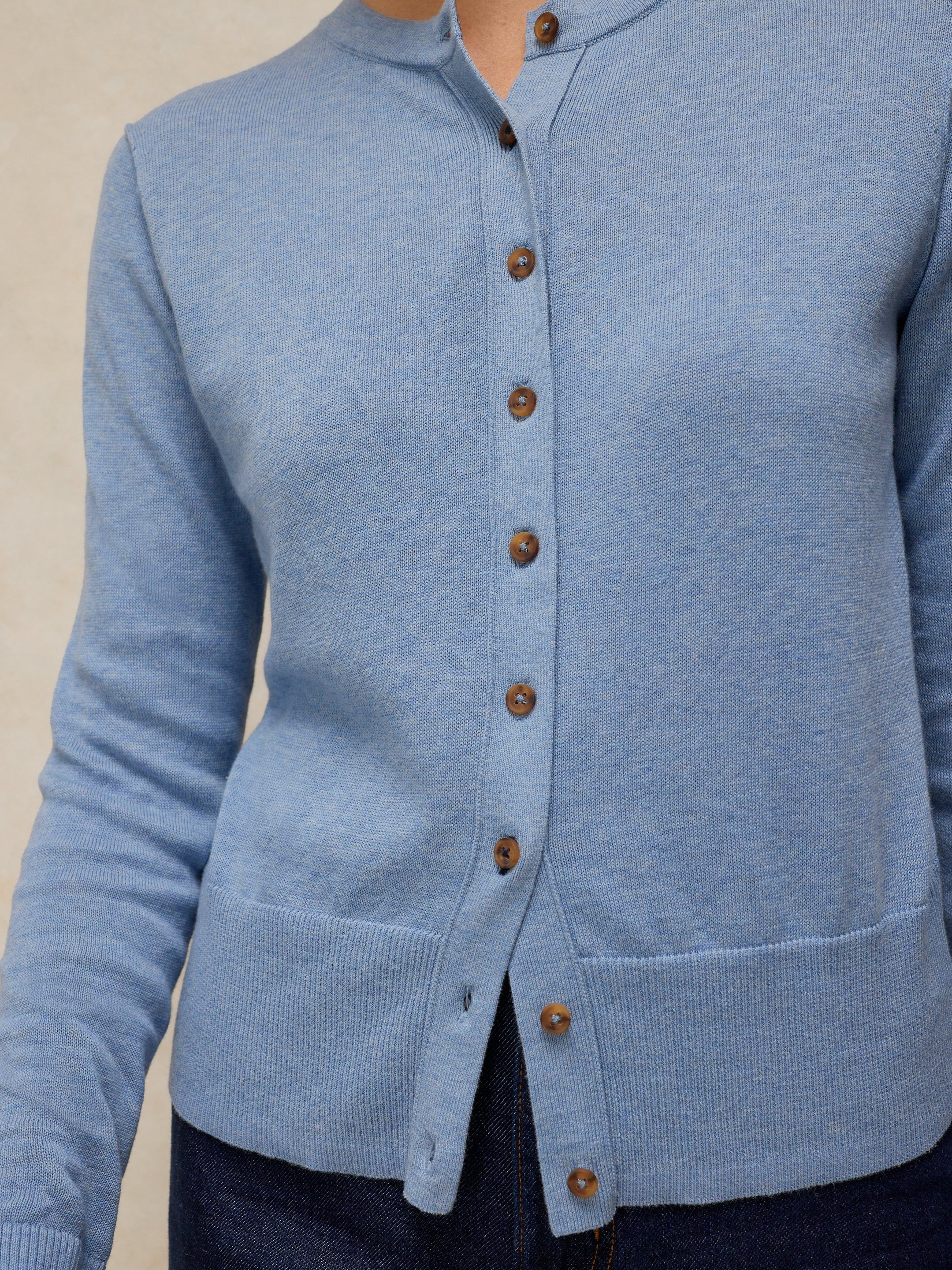 Light blue cardigan with brown buttons on a neutral background