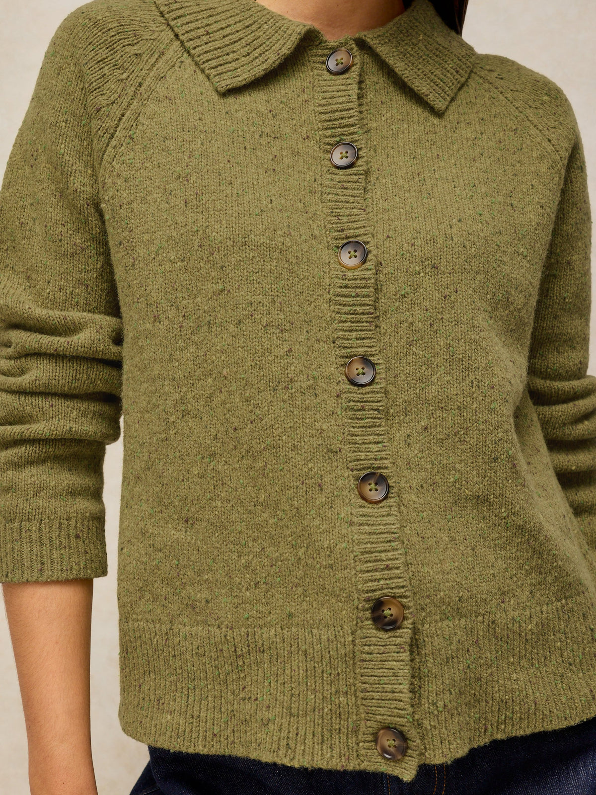 An olive green knit cardigan sweater with a collar and brown buttons, shown on a model.