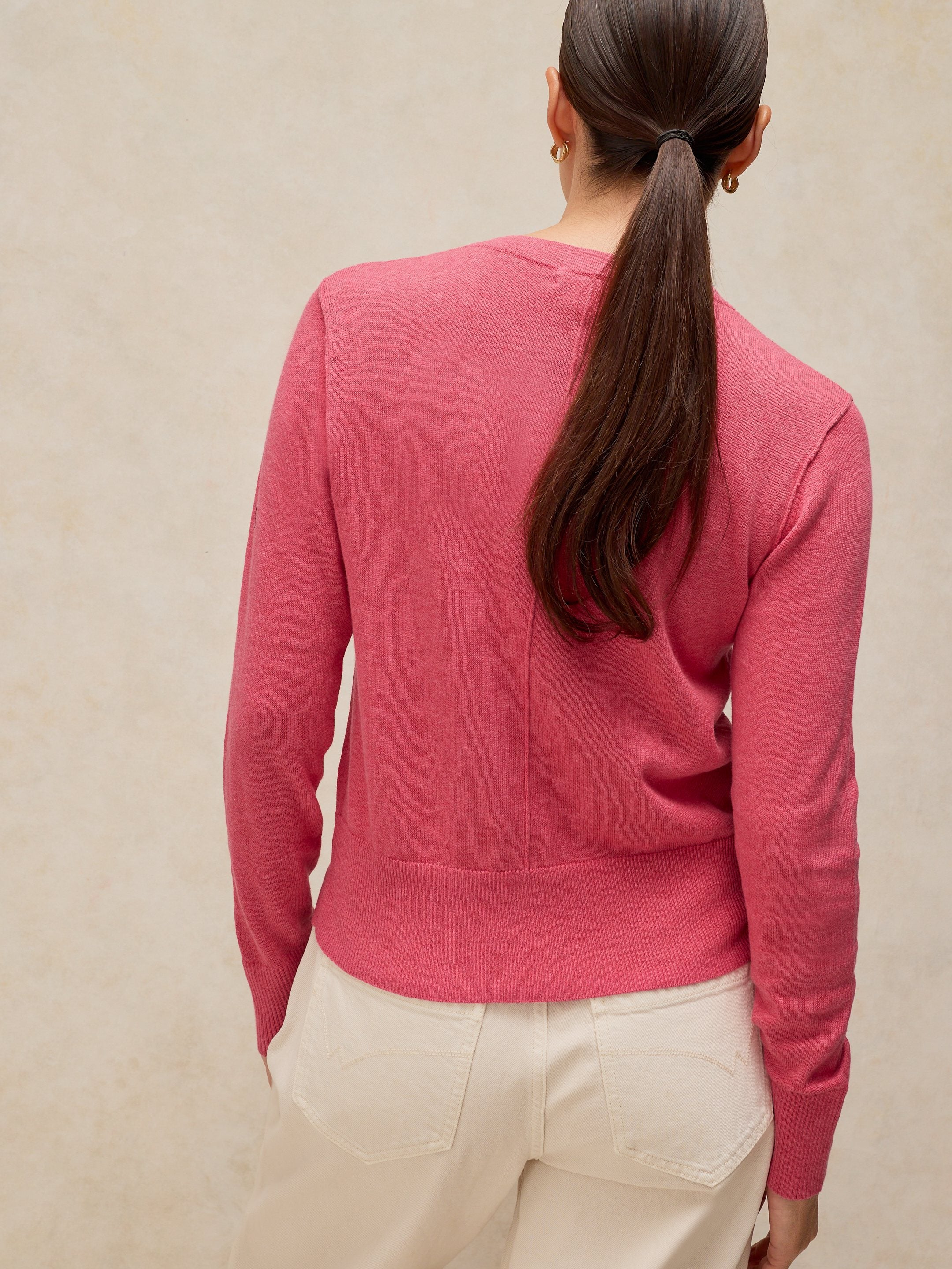 Person wearing a pink sweater against a beige background