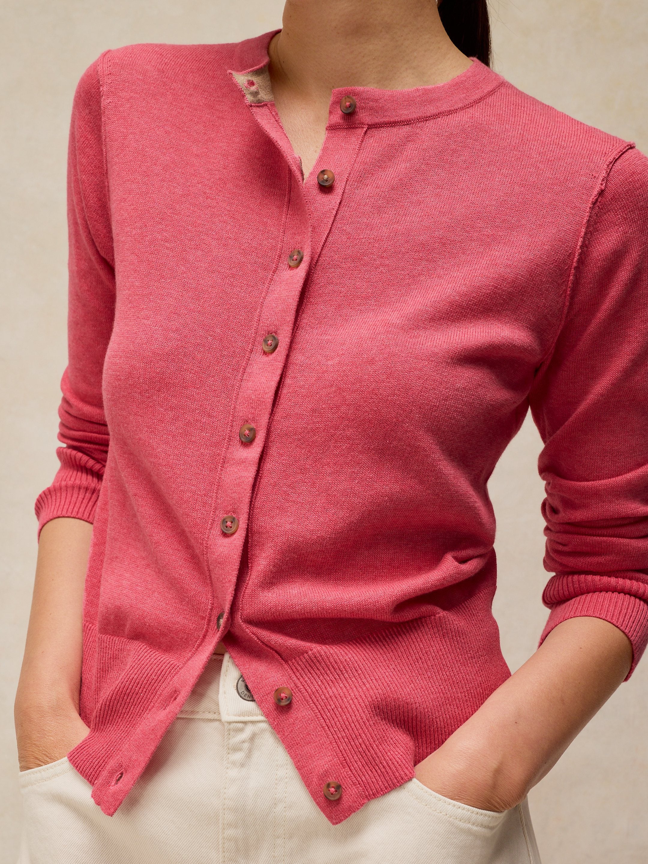 Pink cardigan worn by a person on a beige background