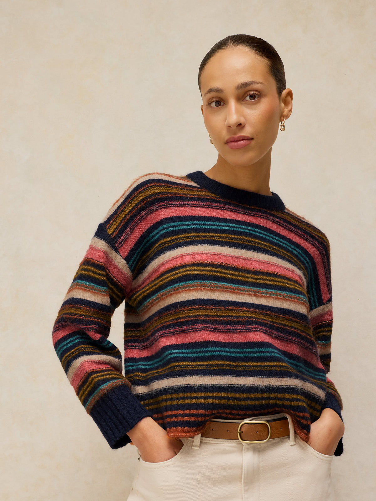 Person wearing a multicolored striped sweater against a neutral background