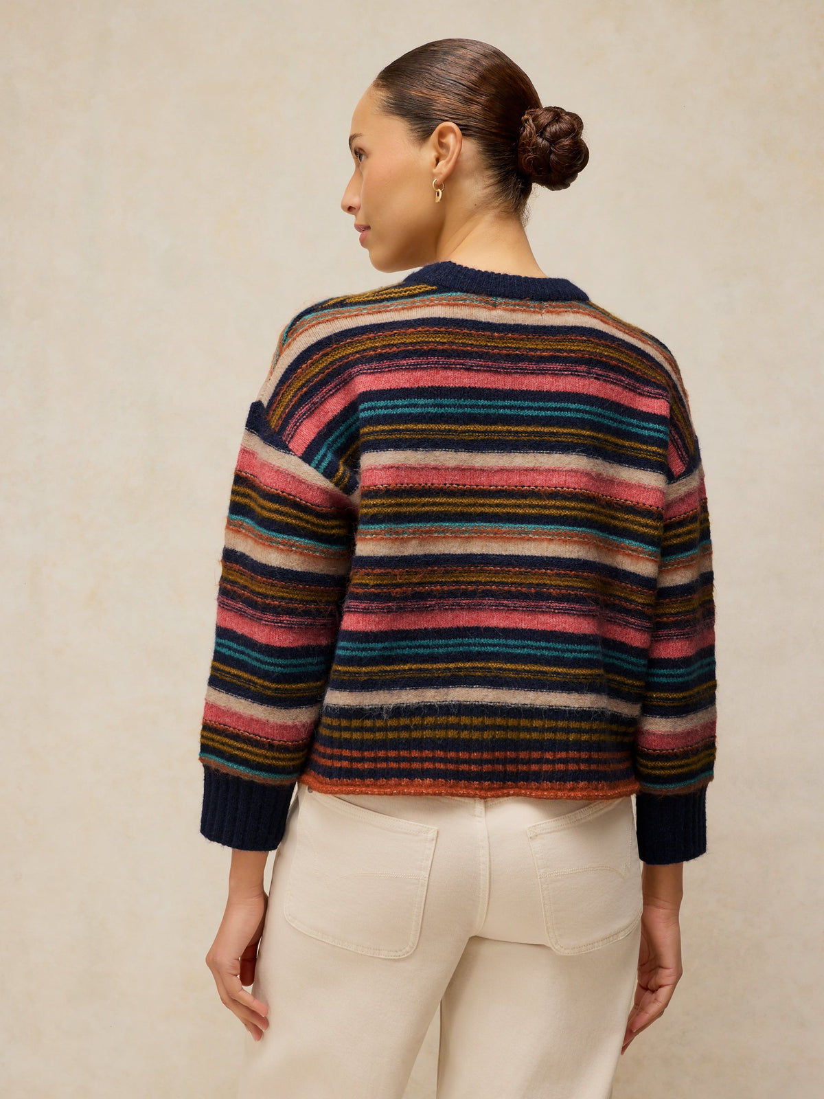 Person wearing a multicolored striped sweater against a beige background