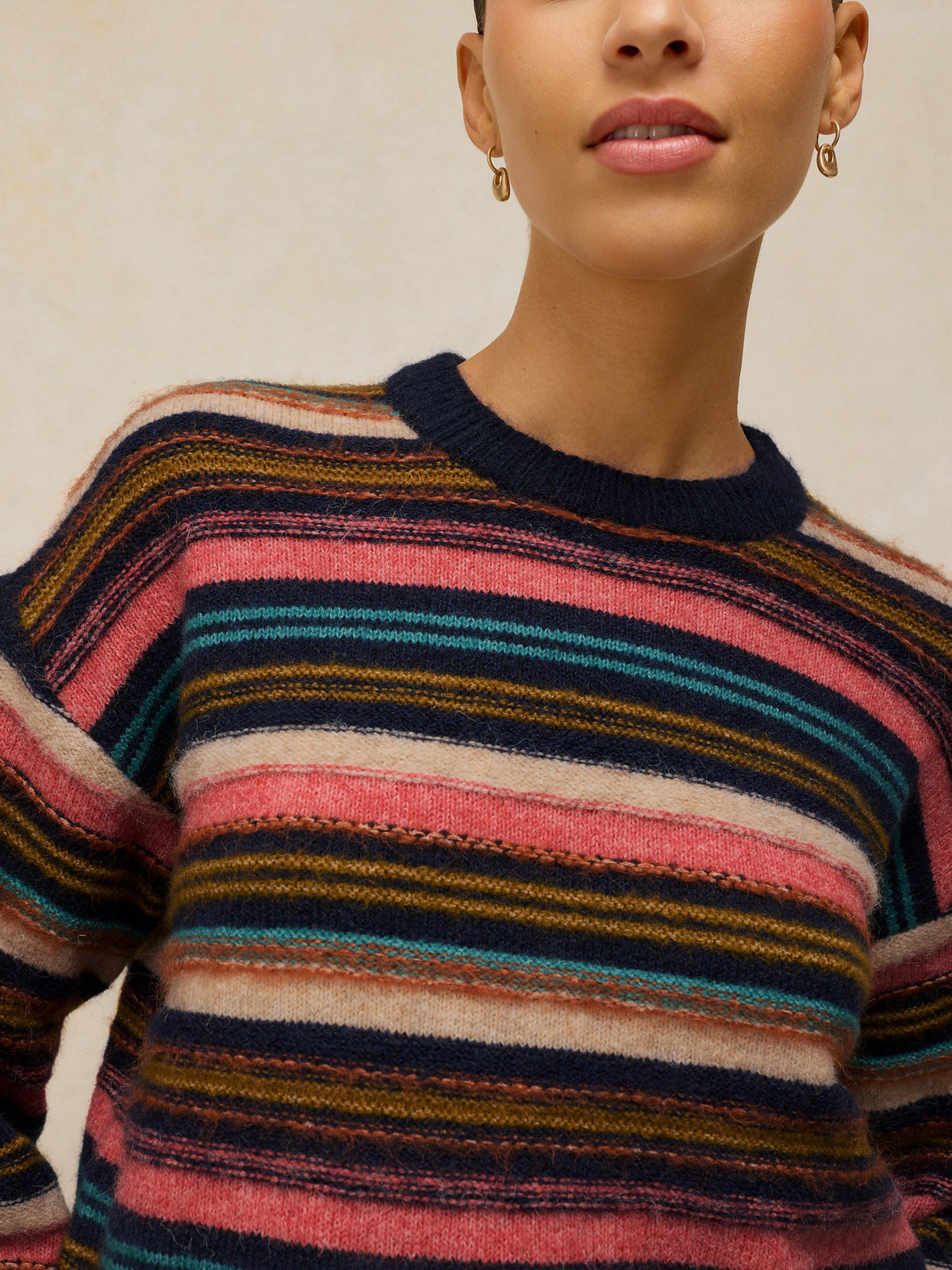 Person wearing a multicolored striped sweater against a neutral background