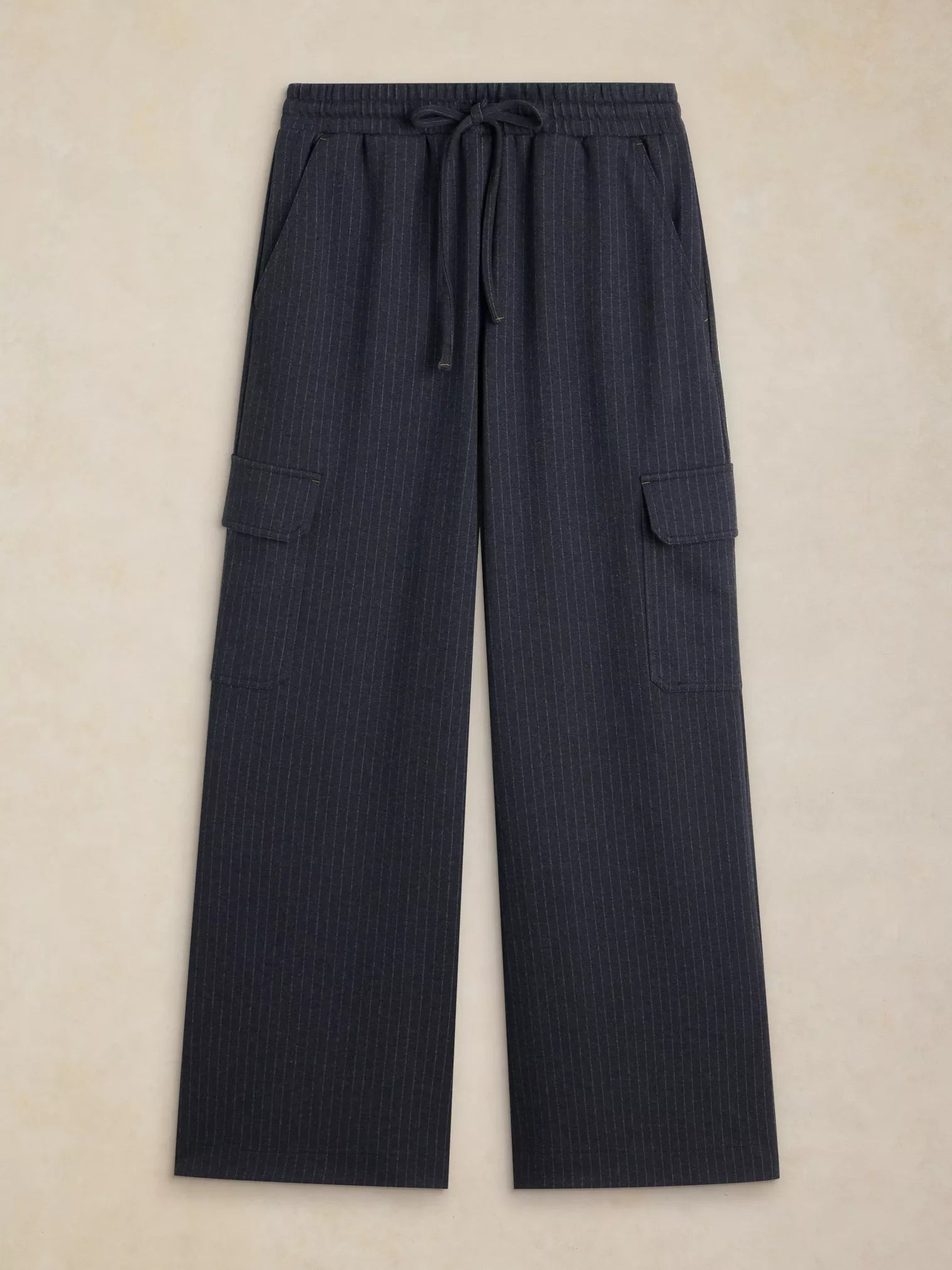 Dark navy pinstriped wide-leg cargo pants with an elastic drawstring waist, laid flat on a textured beige background.