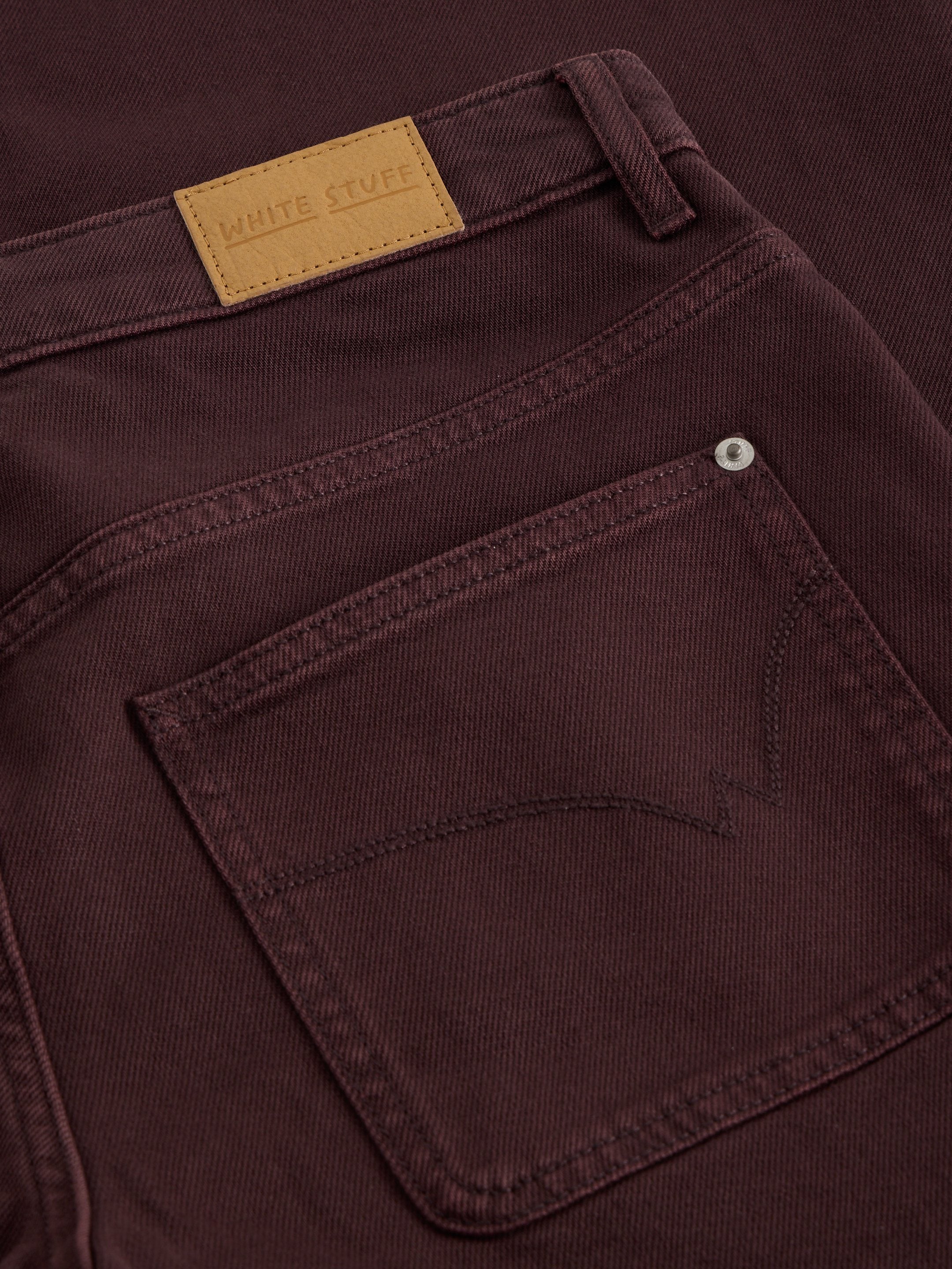 Close-up of a maroon pants pocket with a visible brand label.