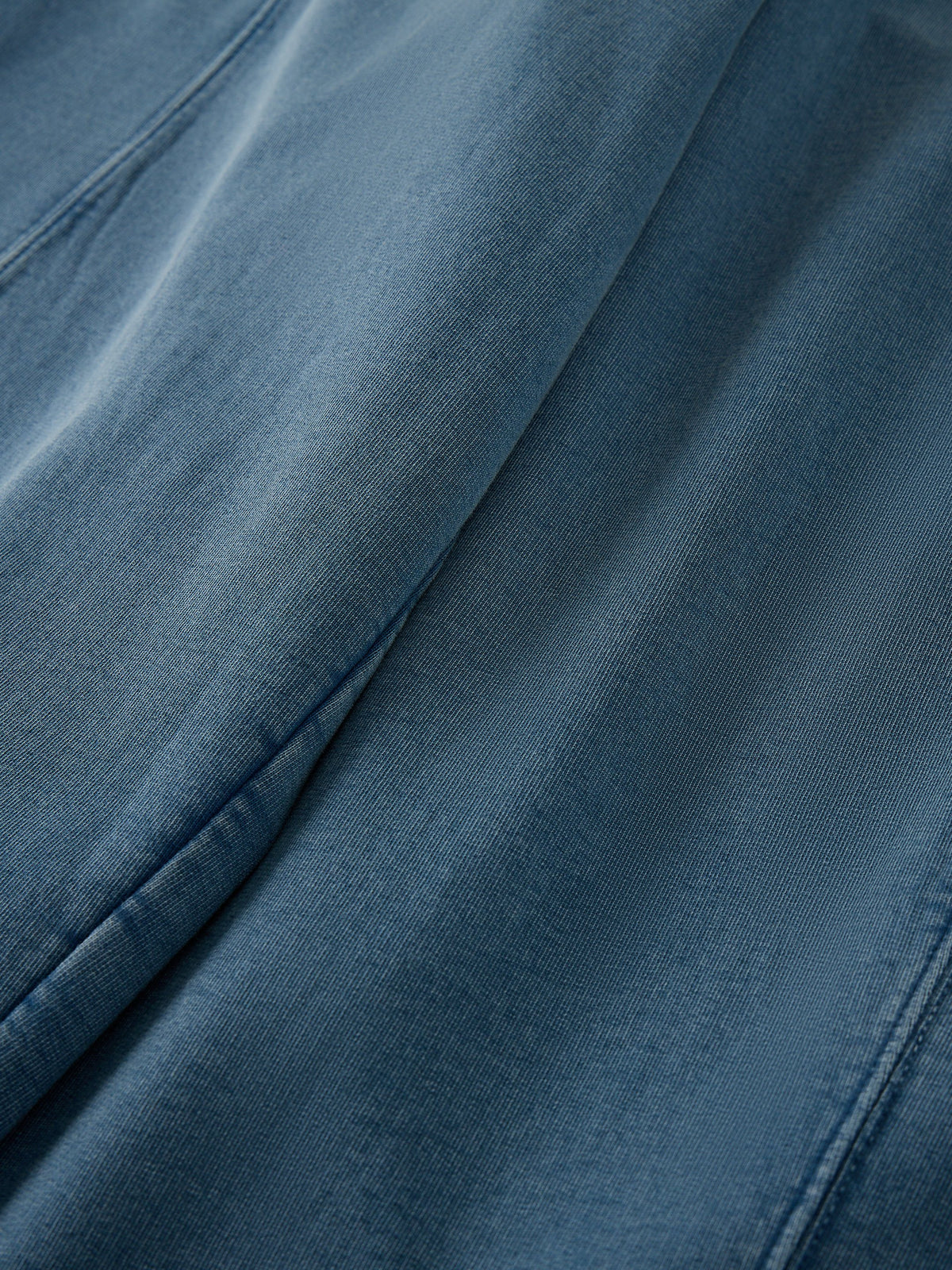 A close-up of blue denim fabric with visible texture and soft folds.