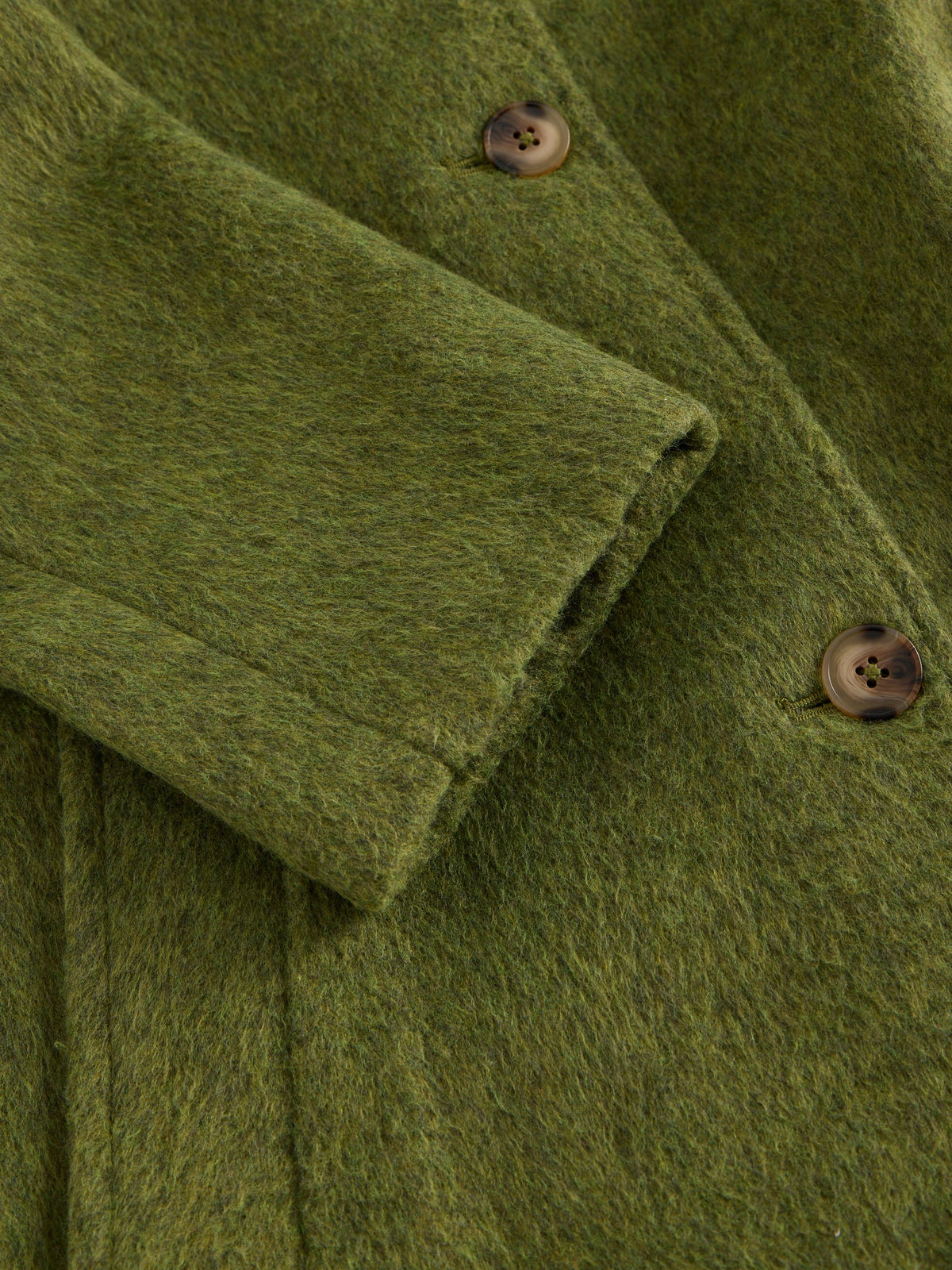 Close-up of an olive green textured wool or felt garment, showing a folded cuff and two brown buttons.