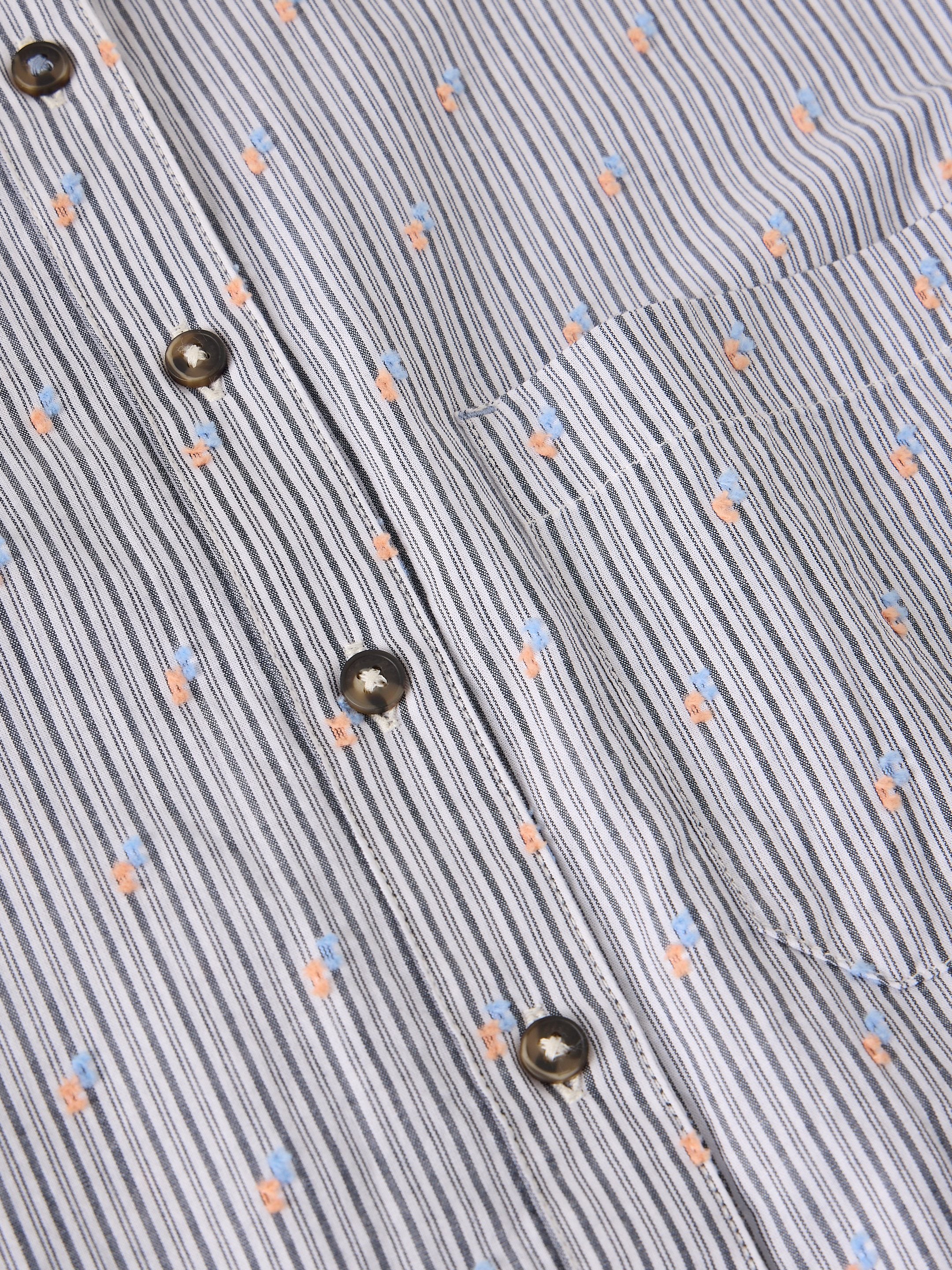 Close-up of a striped button-up shirt fabric with vertical blue, gray, and white stripes, accented with small peach and light blue floral motifs and dark metal buttons.