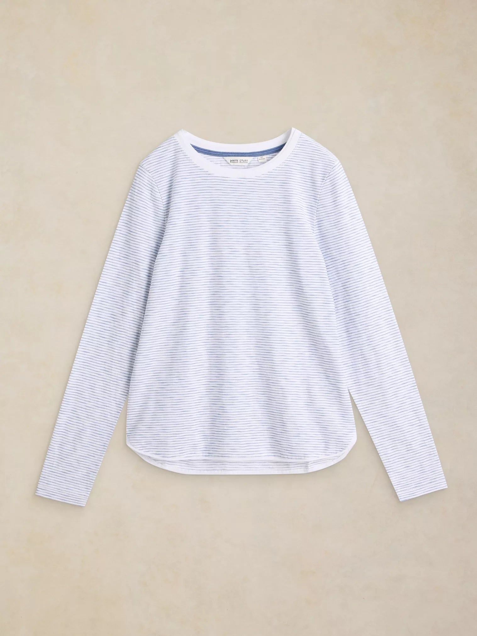 A long-sleeve crewneck top with fine horizontal stripes in white and light blue, laid flat against a textured beige background.