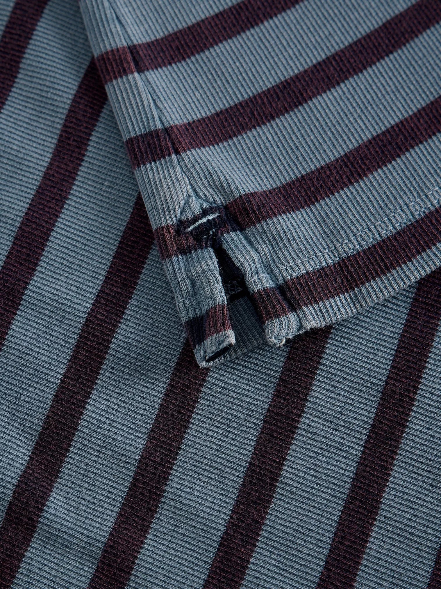 Close-up of a ribbed knit fabric with horizontal stripes in muted blue-gray and dark burgundy.