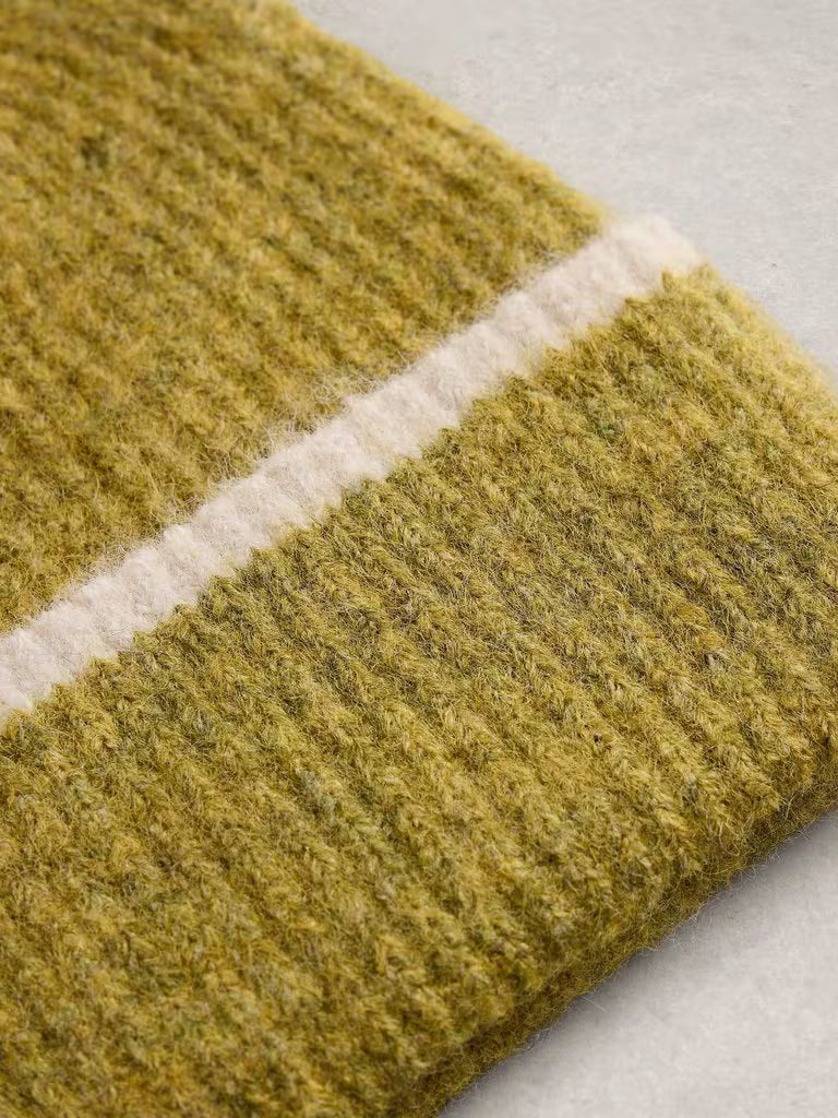 Close-up of a textured knit fabric in a muted olive yellow-green with a contrasting off-white stripe, laid on a light gray surface.