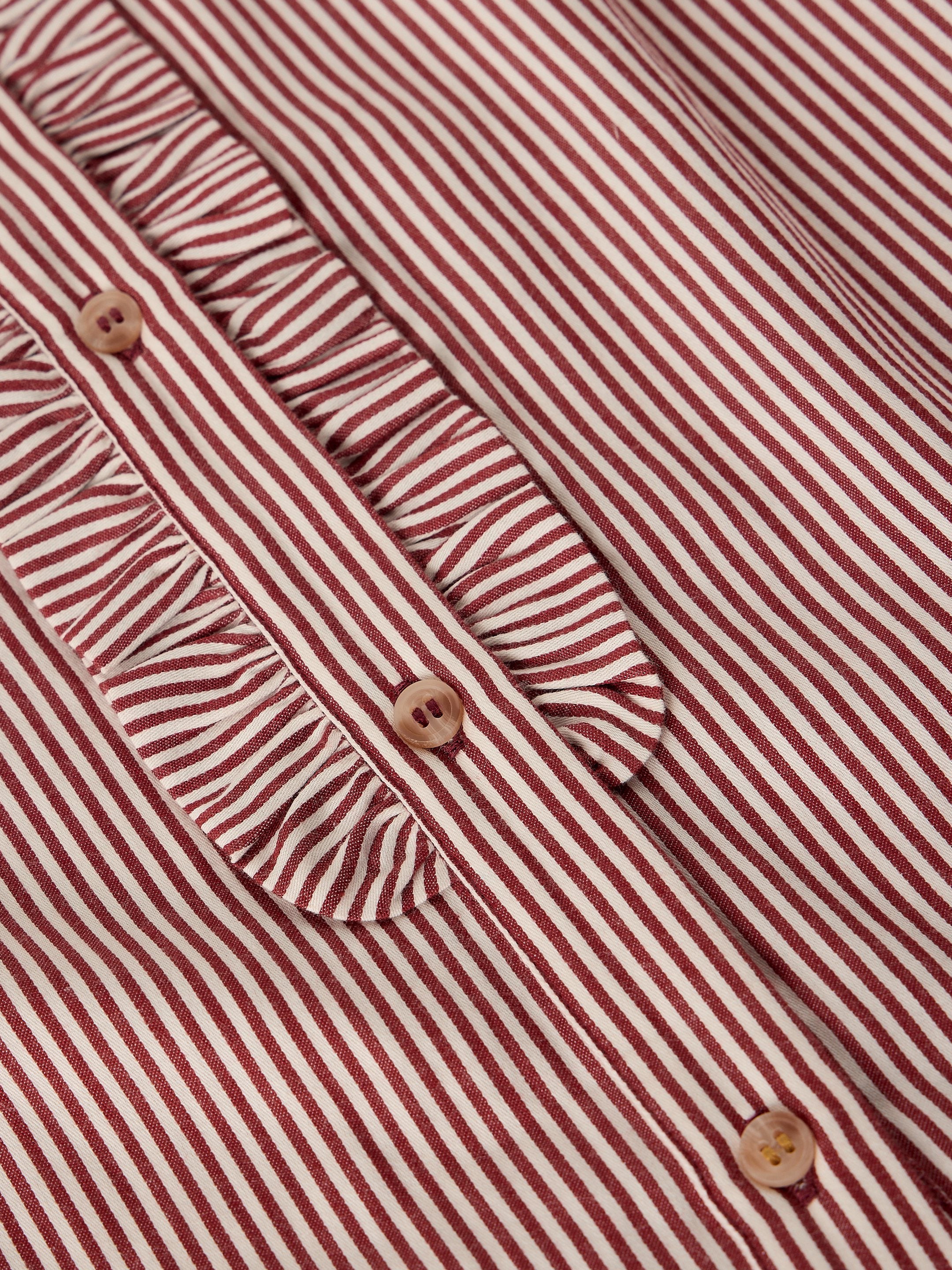 Close-up of a red and white striped blouse with a ruffled collar and decorative buttons.
