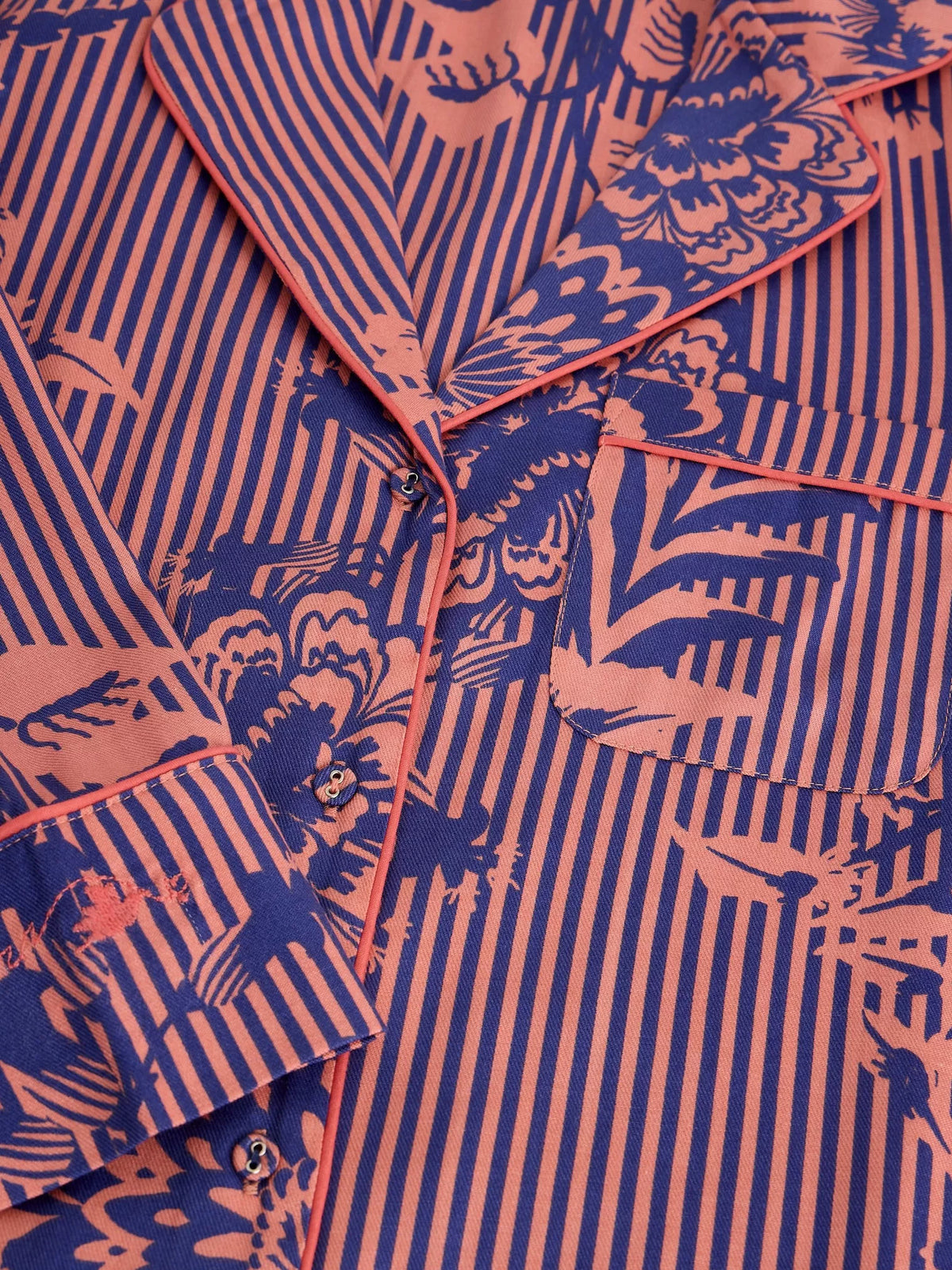 Close-up of a long-sleeve button-up shirt with a blue and orange floral print, vertical orange stripes, and orange piping along the collar, placket, and pocket.