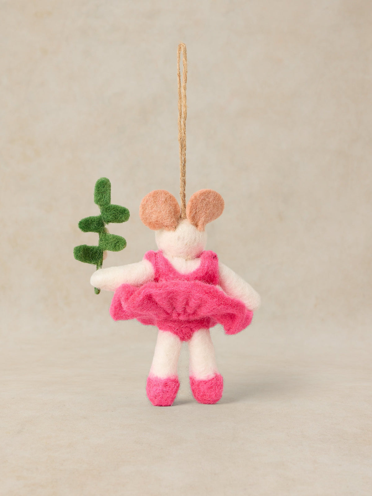 A felted wool mouse ballerina ornament hanging from a natural jute string. The mouse has pink felted ears, a bright pink tutu and shoes, and holds a small green leaf, set against a neutral beige background.